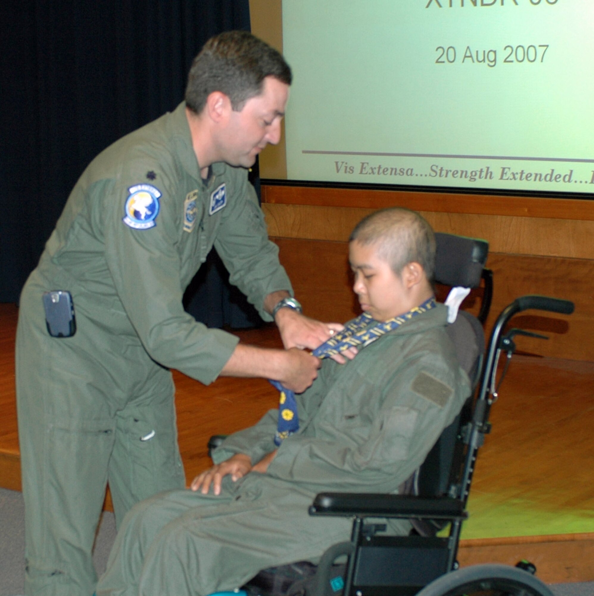 Lt. Col. Jim Craft, 6th Air Refueling Squadron commander, provides Mitchell Louie with the squadron scarf, patches, dog tags and a coin before setting out to experience his day as a pilot. During his day, Mitchell toured the air traffic control tower, refueled fighters using the KC-10 boom operator trainer simulator and with the help of a simulator, piloted a KC-10 Extender around the San Francisco Bay and other exotic locations. (U.S. Air Force photo/Airman 1st Class Kristen Rohrer)