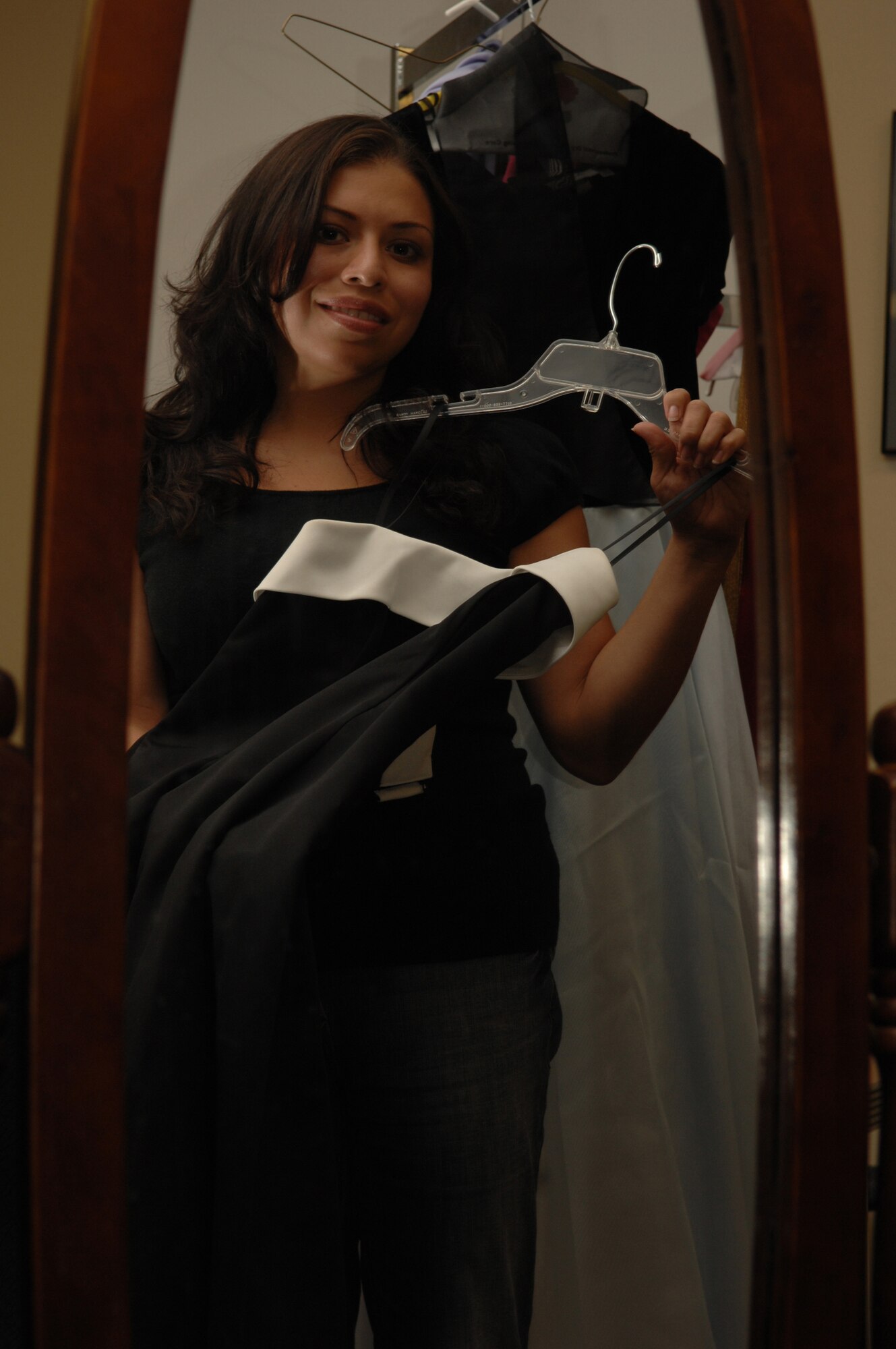 Staff Sgt. Jessica Quintero, instructor at the First Term Airmen's Center, holds up one of the 39 dresses available for spouses to choose from Saturday, Aug. 25, to wear to the Nellis Air Force Ball at the Mirage Sept. 8.  (Photo by Senior Airman Larry Reid)