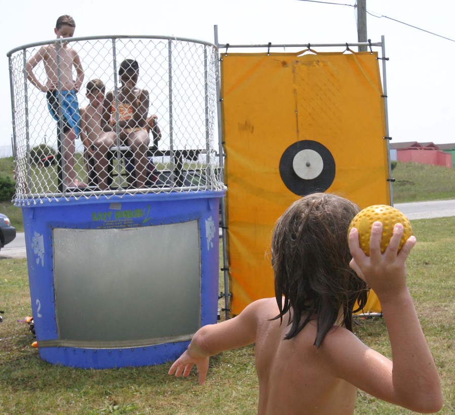 Children attempt to submerge their friends by heaving softballs at a dunking booth at the Marine Special Operations Support Group hosted Beach Bash at Onslow Beach here, Aug. 22. The Family Readiness Office organized the Beach Bash party for MSOSG Marines and their families. The event helps bring families together, improving the support system at home for Marines.