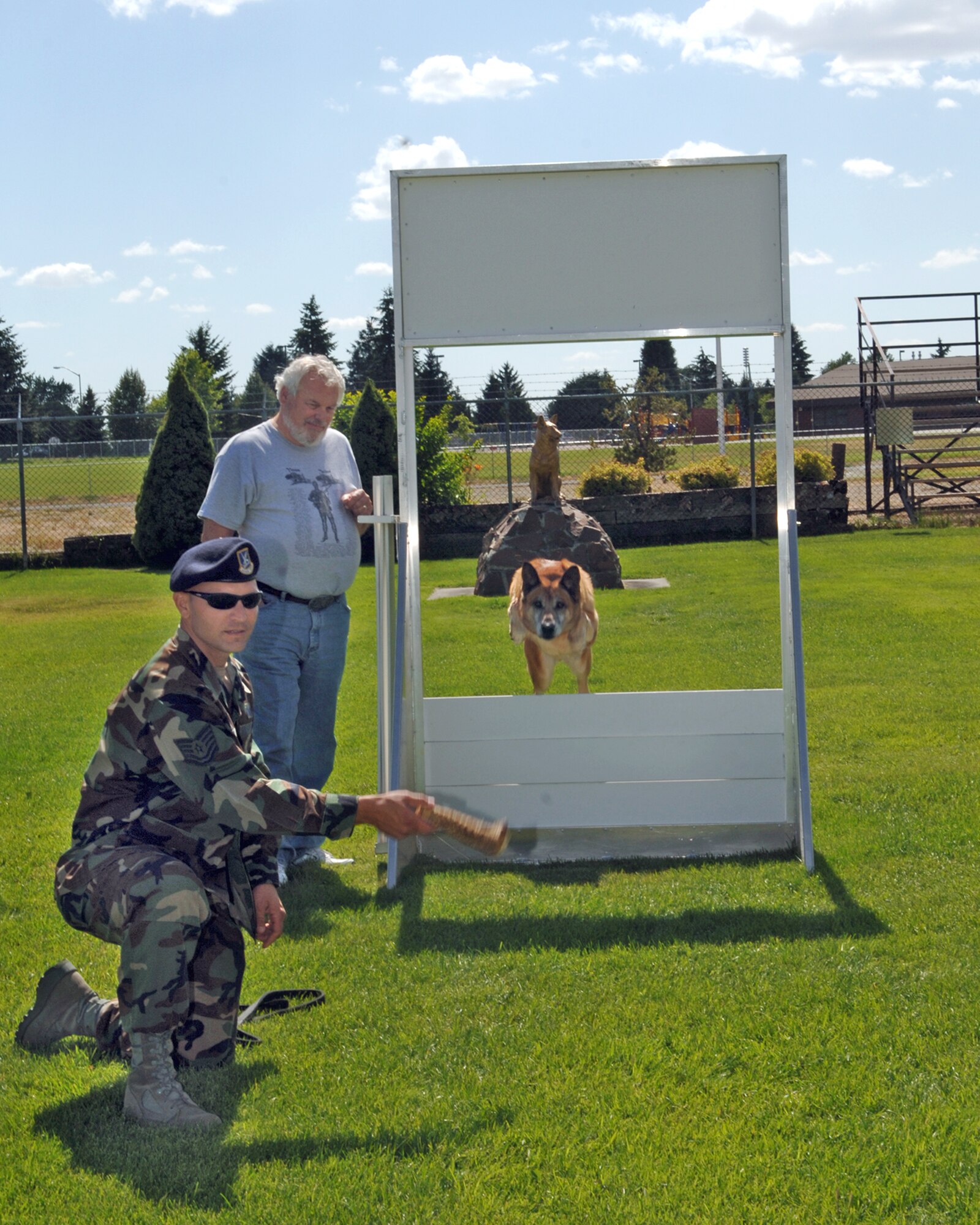 FAIRCHILD AIR FORCE BASE, Wash. -- David Adams watches as Tico jumps through a window obstacle at the military working dog facility here. Tech. Sgt. Max Talley, 92nd Security Forces Squadron kennel staff, coaxes Tico through the obstacle which teaches the dog how to gain entrance by jumping through an open window. 
Mr. Adams, a former dog handler with the 92nd Bomb Wing, spent the day with Sergeant Talley touring the new facilities and discussing the differences in two eras of dog handling. (U.S. Air Force photo / Airman 1st Class Josh Chapman)
