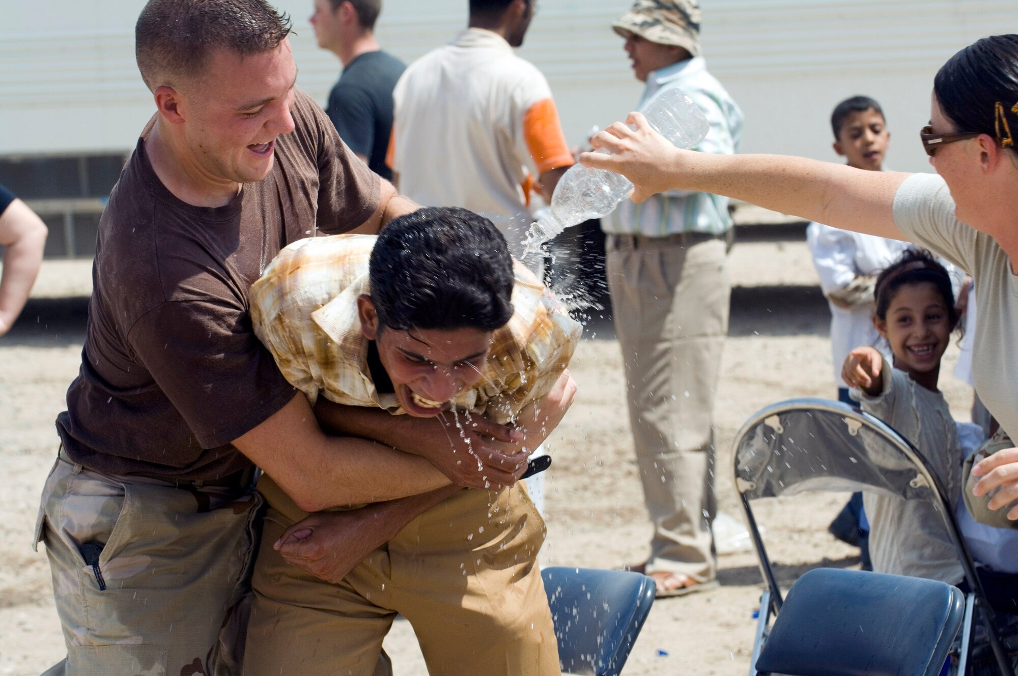 Senior Airman Paul Waldrep holds a young Iraqi boy while Senior Airman Charmaine Garza pours water on him Aug. 21 during a water fight at the Ziggurat in the ancient city of Ur located on Ali Base, Iraq. The boy was one of 80 Iraqi citizens who visited the historical Ziggurat and interact with Airmen from Ali Base. The Ali First Four Council sponsored the visit. This was the first time in more than 10 years that Iraqi civilians have been allowed to step on the grounds of the historical sight, which includes the house of the biblical prophet Abraham. Airman Waldrep is a member of the 407th Expeditionary Civil Engineer Squadron, and Airman Garza is a member of the Expeditionary Security Forces Squadron. (U.S. Air Force photo/Master Sgt. Robert W. Valenca)