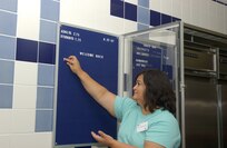 Leonorilda Carrillo prepares the Stacey Junior/Senior High school's cafeteria menu board Aug. 20. Permission was granted on Aug. 16 for off-base military children to attend Lackland ISD schools because of declining enrollment numbers due to North Wherry housing closure. (USAF photo by Alan Boedeker)                                