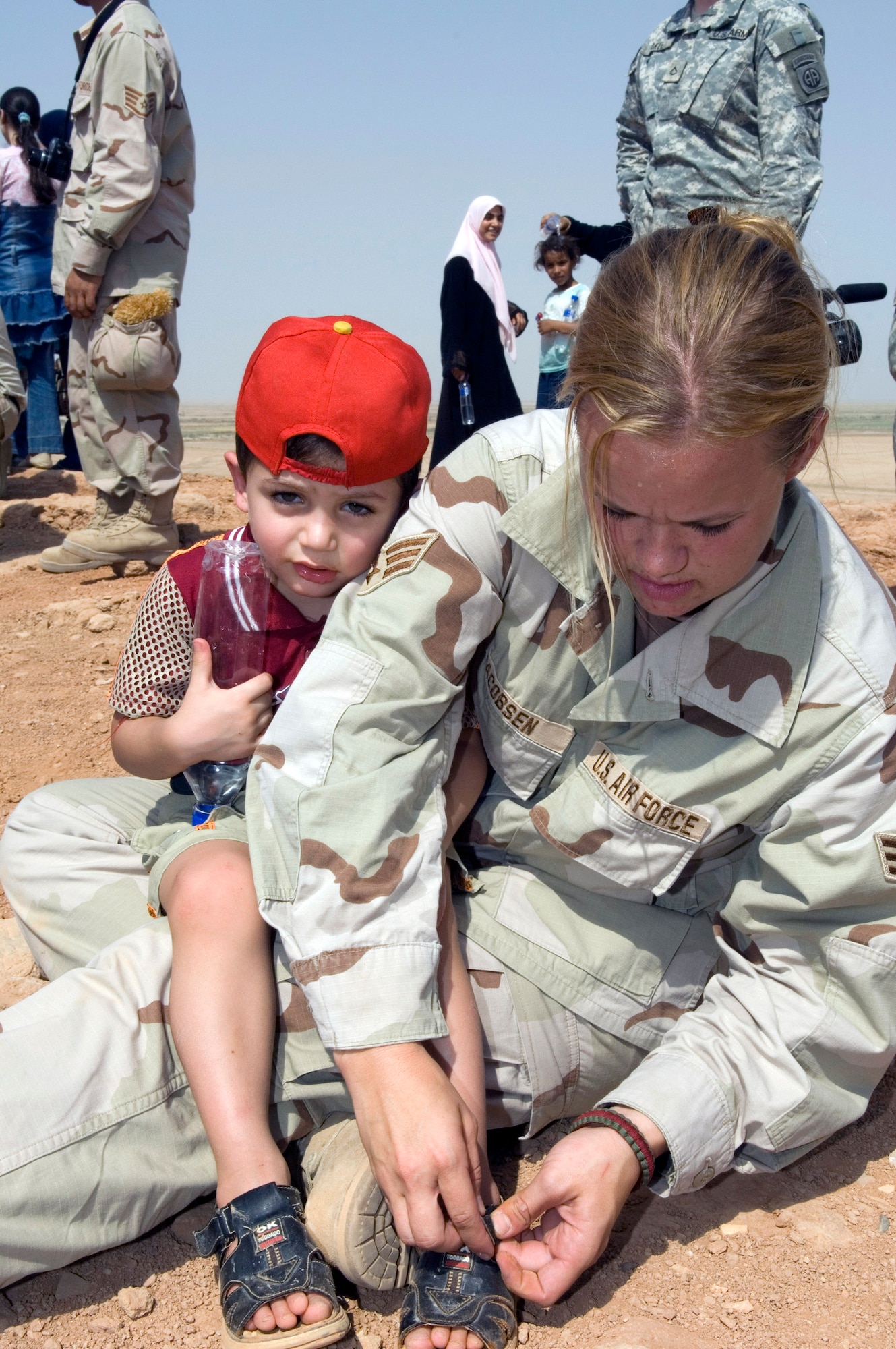Senior Airman Ashley-Louise Jacobsen helps a young Iraqi boy get a rock out of his sandal during an Aug. 21 visit by 80 Iraqi nationals to the historical Ziggurat located on Ali Air Base, Iraq. The Ali AB First Four Council sponsored the visit. This is the first time in more than 10 years that Iraqi civilians have been allowed to step on the grounds of the historical site, which was built in the ancient city of Ur and includes the house of the biblical prophet Abraham. Airman Jacobsen is a member of the 407th Expeditionary Logistics Readiness Squadron at Ali AB. (U.S. Air Force photo/Master Sgt. Robert W. Valenca) 