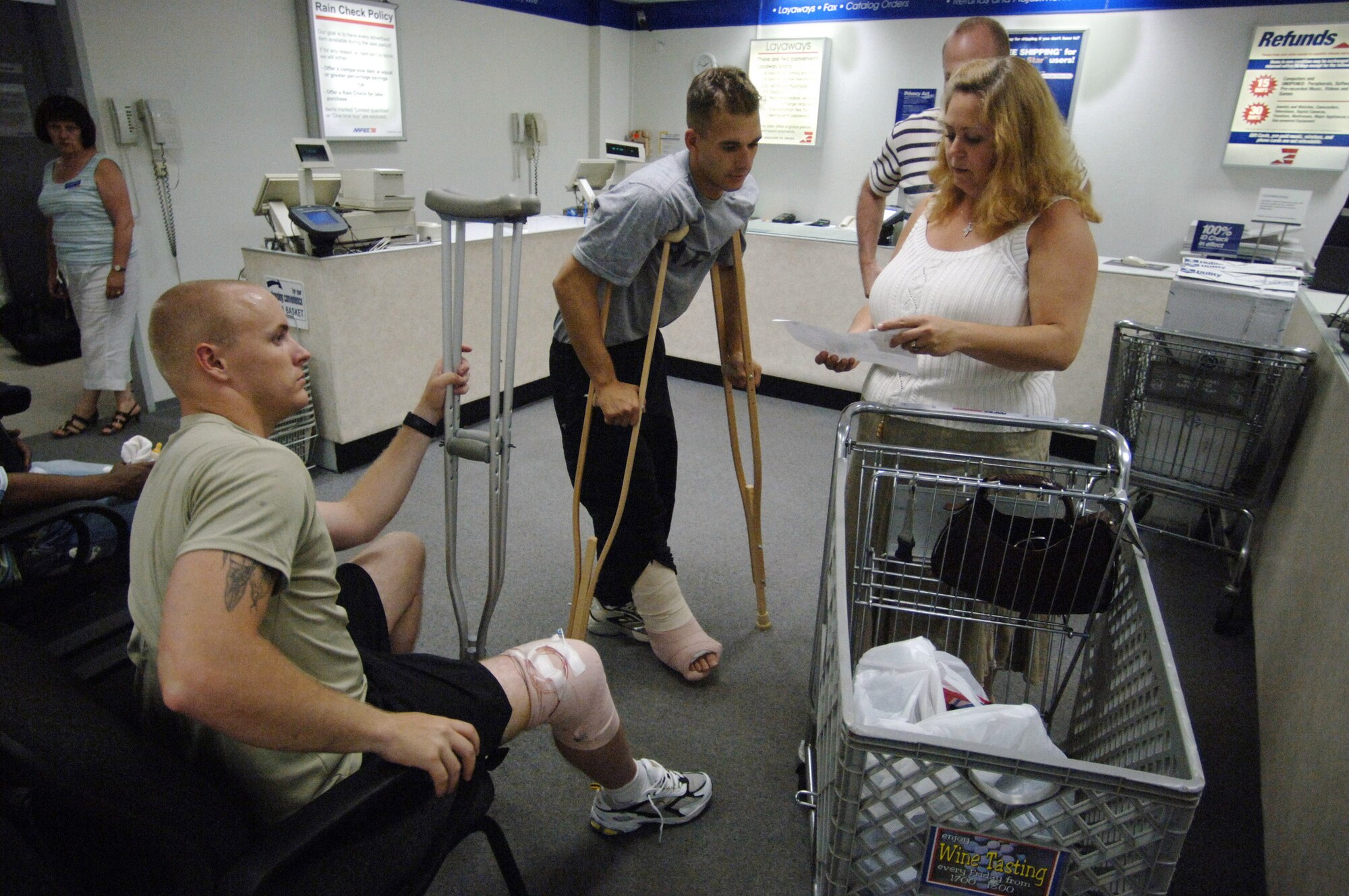 Judy Arnts and husband Senior Master Sgt. Phillip Arnts assist Staff Sgt. Sean Knight and Cpl. Jared Morris, 82nd Airborne Division soldiers, with using $250 gift vouchers donated by the Army Air Force Exchange Service to purchase much-needed replacements for clothing items lost while being medically evacuated from Afghanistan. The Arnts are actively involved in a chartered non-profit organization called "Mission: Just Us" that aids wounded service members in outpatient status at Landstuhl Regional Medical Center by offering assistance with personal errands and free-transportation to local eating establishments.  (U.S. Air Force photo/Master Sgt. Scott Wagers)