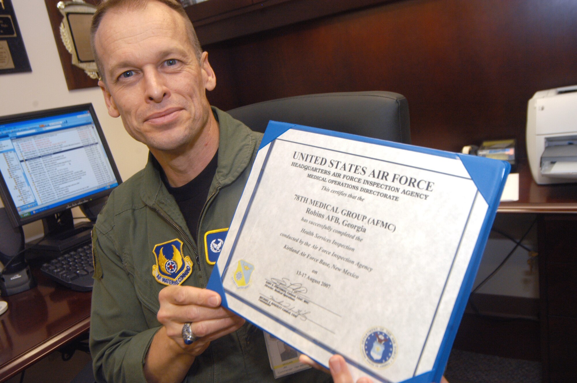 Col. Jim McClain, 78th Medical Group commander, shows off the Health Services Inspection certificate from the Air Force Inspection Agency.  U. S. Air Force photo by Sue Sapp  