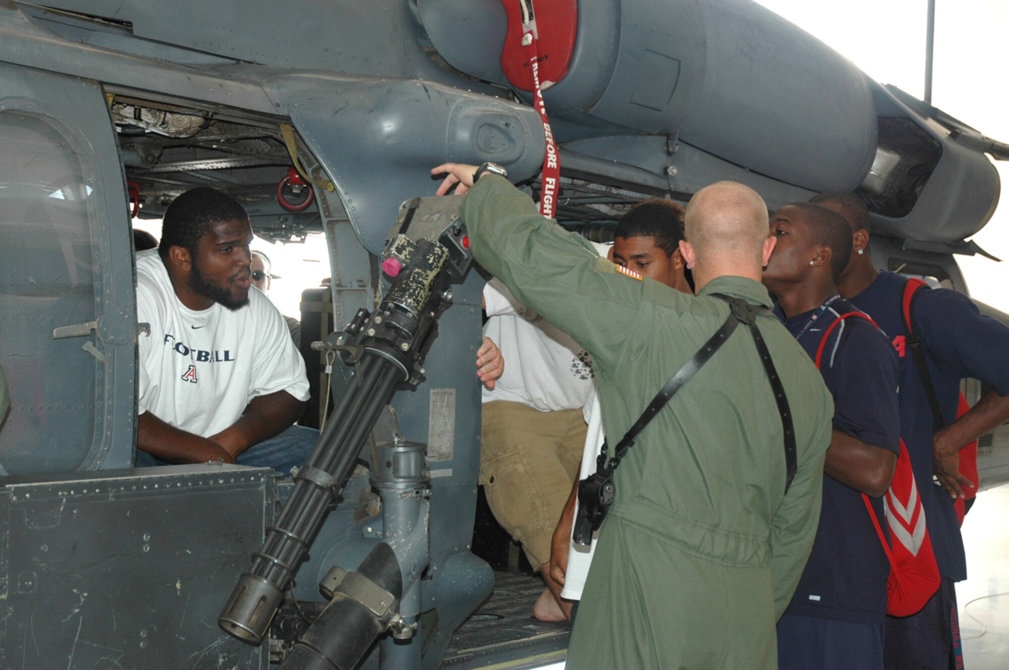 Staff Sgt. Jason Davis, an aerial gunner from the 55th Rescue Squadron here, explains the HH-60 Pavehawk “minigun” to members of the University of Arizona’s football team during their visit to the base Aug. 17. "They came to see how we teach and become a team – how we motivate," said 55th RQS Commander Lt. Col. Massey, who organized the visit after the 55th RQS previously joined UA football coaches in a physical training session at UA’s Arizona Stadium. Upon their departure, the team presented the squadron with a football helmet autographed by all the coaches. “We really appreciate what you all do,” said Mike Stoops, UA’s head football coach. (U.S. Air Force photo/Airman 1st Class Jamie L. Coggan)