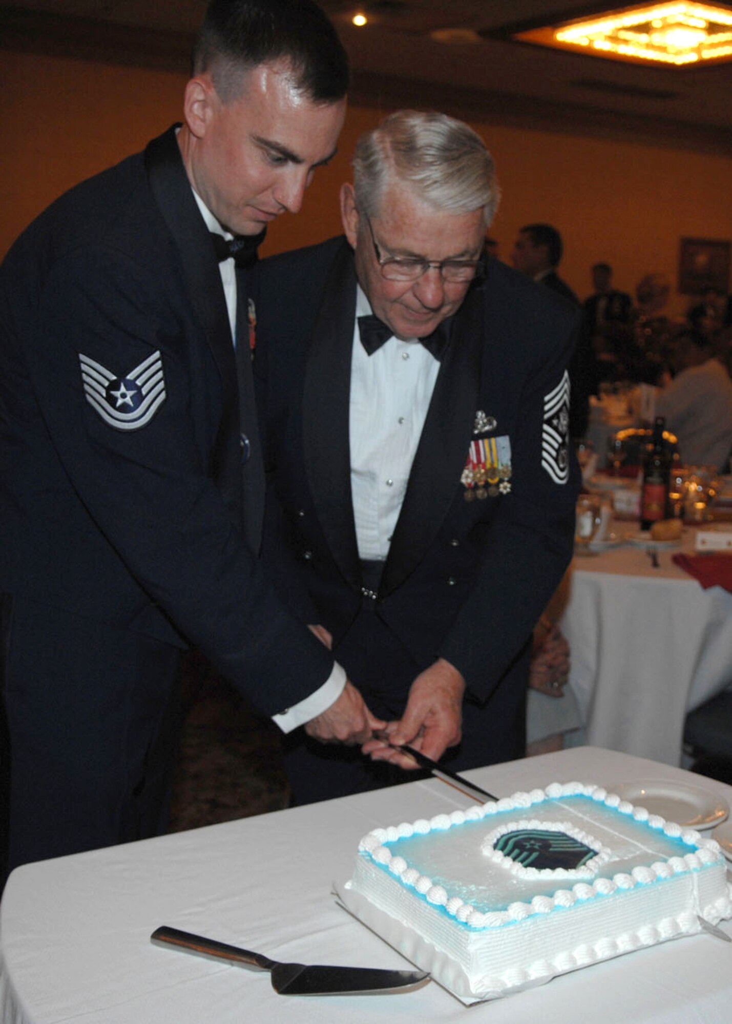 Tech. Sgt. Paul Dunbar of the 355th Medical Operations Squadron here cuts the ceremonial cake with Robert Gaylor, the fifth chief master sergeant of the Air Force, during the first ever Davs-Monthan Senior NCO Induction Ceremony July 27 at the Holiday Inn Tucson Airport North hotel. Sergeant Dunbar had the highest line number of all the new D-M master sergeants. (U.S. Air Force photo/Senior Airman Christina D. Kinsey)