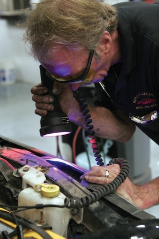 Duane Dramen, a mechanic at the station?s Auto Service Center, uses a black light to check the Freon lines for leaks after mixing dye in with the Freon, here Aug. 22.