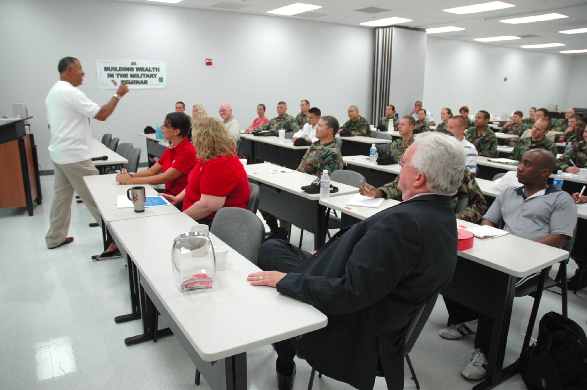 Clayton Moore, a community readiness technician at the Airman and Family Readiness Center here, speaks to a group of more than 30 people attending the Building Wealth in the Military seminar held at the AFRC Aug. 3. Mr. Moore discussed basic principles of fiscal responsibility and investment opportunities, and he then shared the floor with other financial experts from businesses and organizations around the local area. (U.S. Air Force photo/Staff Sgt. Jake Richmond)