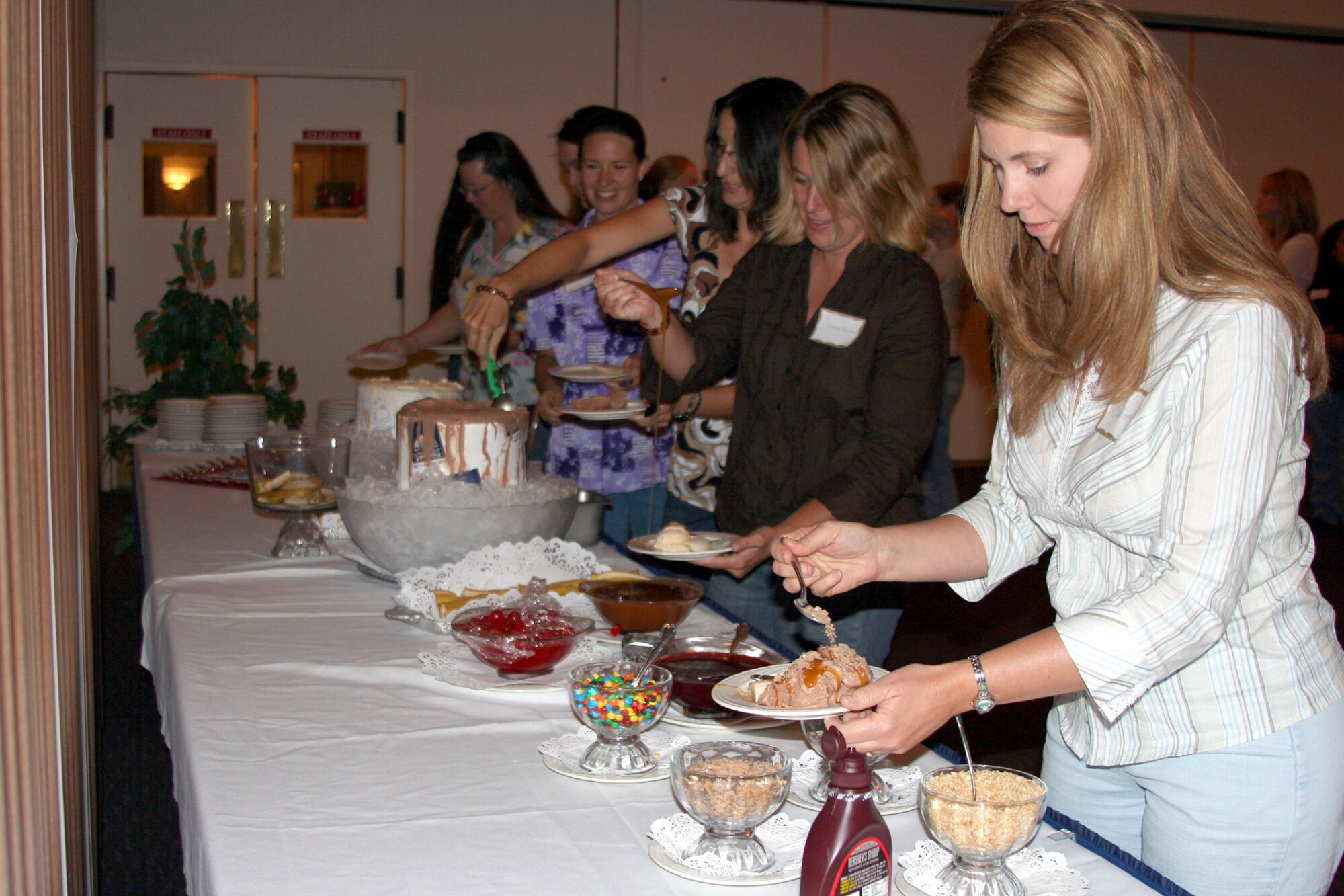 Charlene Ammons, right, spouse of Master Sgt. Michael Ammons, 341st Medical Group, makes her way through the ice cream sundae bar at the Grizzly Bend Club Aug. 23. More than 100 people attended the free ice cream social and membership drive for the Malmstrom Spouse's Club. The MSC is an active and supportive group of spouses who meet for events, while raising and donating more than $10,000 annually. (U.S. Air Force photo/Senior Airman Eydie Sakura).
