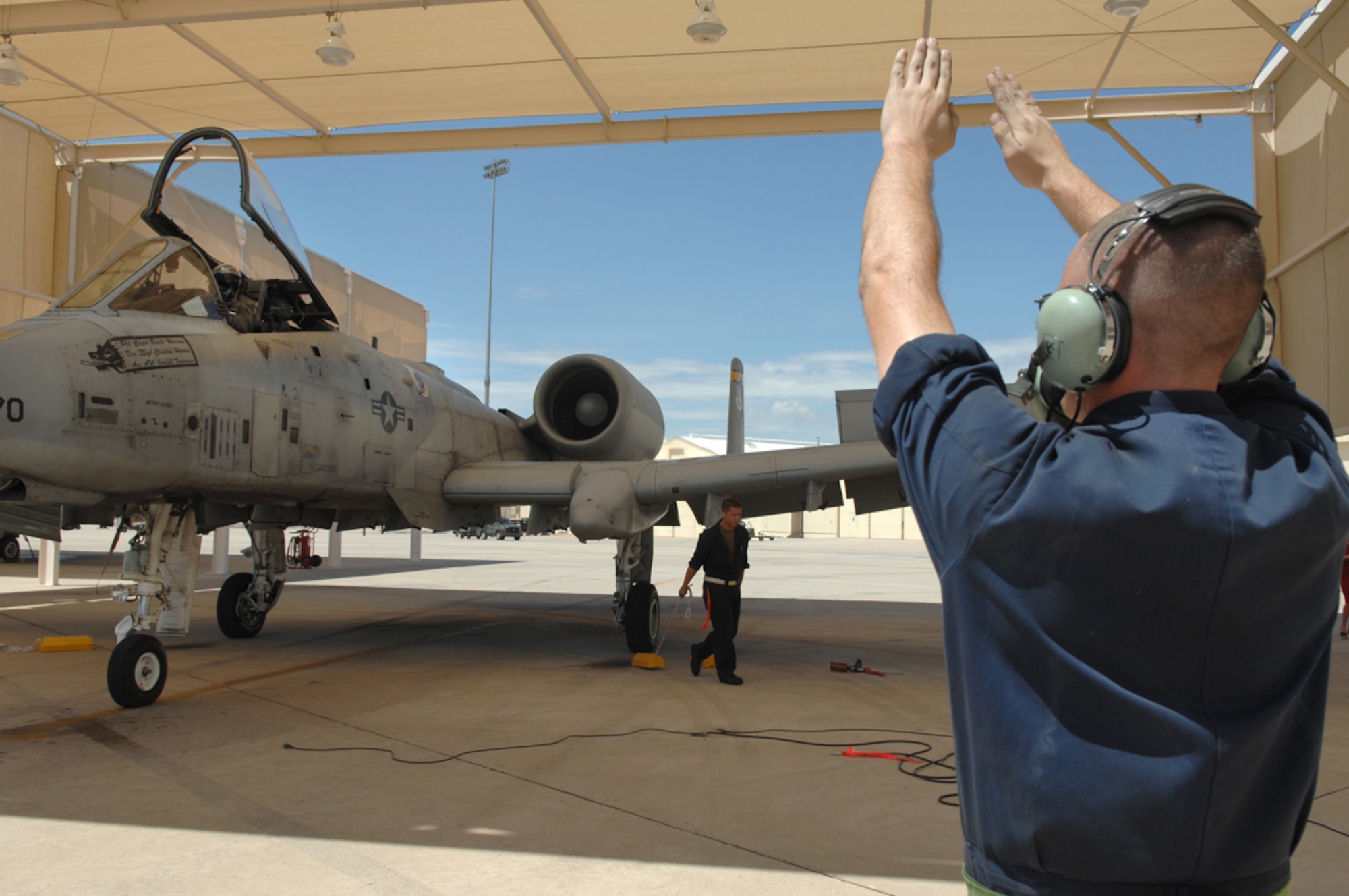 Senior Airman Chad Goucher of the 357th Aircraft Maintenance Unit marshals 2nd Lt. Aaron Cavazos, a 357th Fighter Squadron pilot, and his aircraft under a sun shade here Aug. 2. The landing marked Lieutenant Cavazos' official completion of the first A-10C pilot initial qualification course in Air Force history. The first class had eight pilots training over seven months, focusing on the new A-10C platform, which features major avionics changes from the A-10A. The pilots were also taught the principles of being an attack pilot Wingman: Be in formation to provide mutual support, be on radios and kill the assigned target on the first attempt. (U.S. Air Force photo/Senior Airman Christina D. Kinsey)