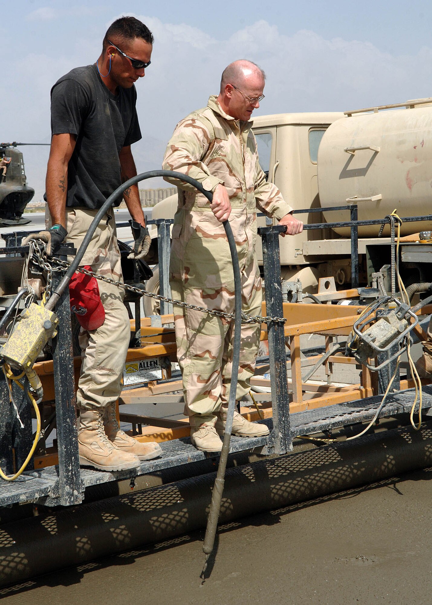 BAGRAM AIRFIELD, Afghanistan -- Staff Sgt. Ryan Bobholz, 1st Expeditionary RED HORSE Group, instructs Chief Master Sgt. David Williamson, 455th Air Expeditionary Wing command chief, on how to use the vibe. The vibe is a metal tube at the end of a thick cable that sends vibrations into the wet concrete in order to spread it out and settle it as it is poured. Chief Williamson and Brig. Gen. Bill Hyatt, 455th AEW commander, visited the RED HORSE Airmen to view the progress they had made and lend a helping hand from senior leadership. (U.S. Air Force photo by Staff Sgt. Craig Seals)
