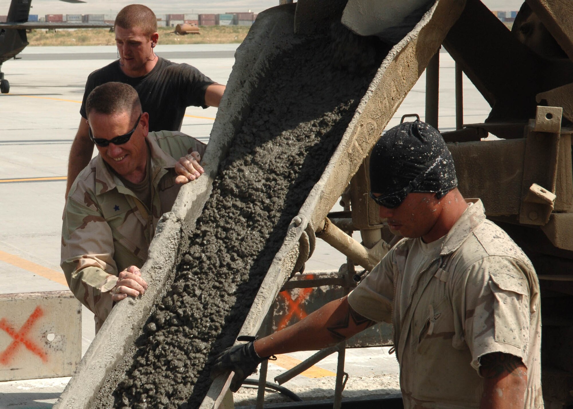 BAGRAM AIRFIELD, Afghanistan -- Brig. Gen. Bill Hyatt (left), 455th Air Expeditionary Wing commander, helps Senior Airman Miguel Gastelum, 1st Expeditionary RED HORSE Group, pour concrete on the Steel Beach portion of the helicopter area of the flightline at Bagram Airfield, Afghanistan. Gen. Hyatt and Chief Master Sgt. David Williamson, 455th AEW command chief, visited the RED HORSE Airmen to view the progress they had made and lend a helping hand from senior leadership. (U.S. Air Force photo by Staff Sgt. Craig Seals)