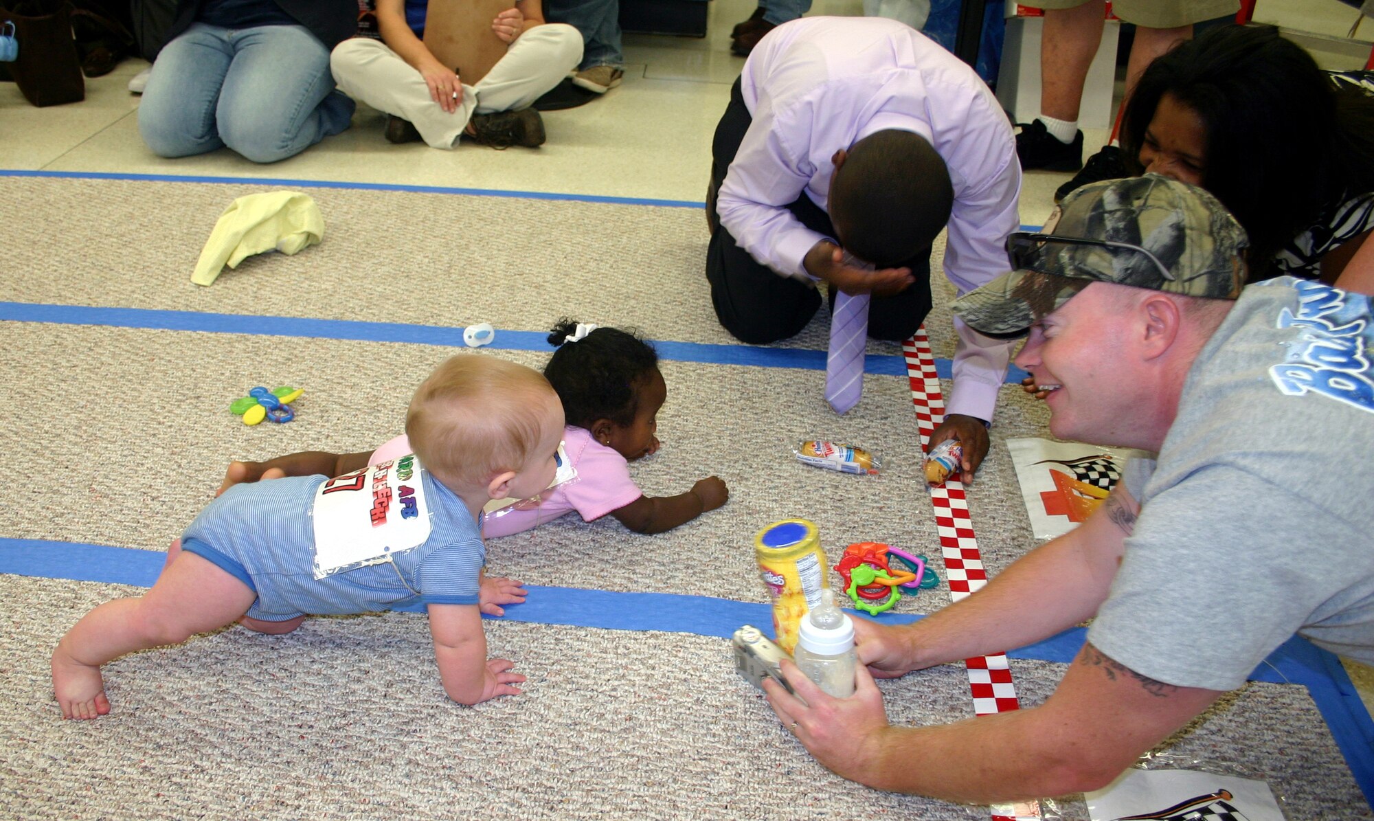 L.J. Sealey and Maryssa Menges engage in a neck-and-neck race toward the finish line during the Hotter'N Heck diaper derby at the Commissary Aug. 26.  Sealey won second place, while Menges took home third in the 0-9 months category. (U.S. Air Force photo/Staff Sgt. Tonnette Thompson)