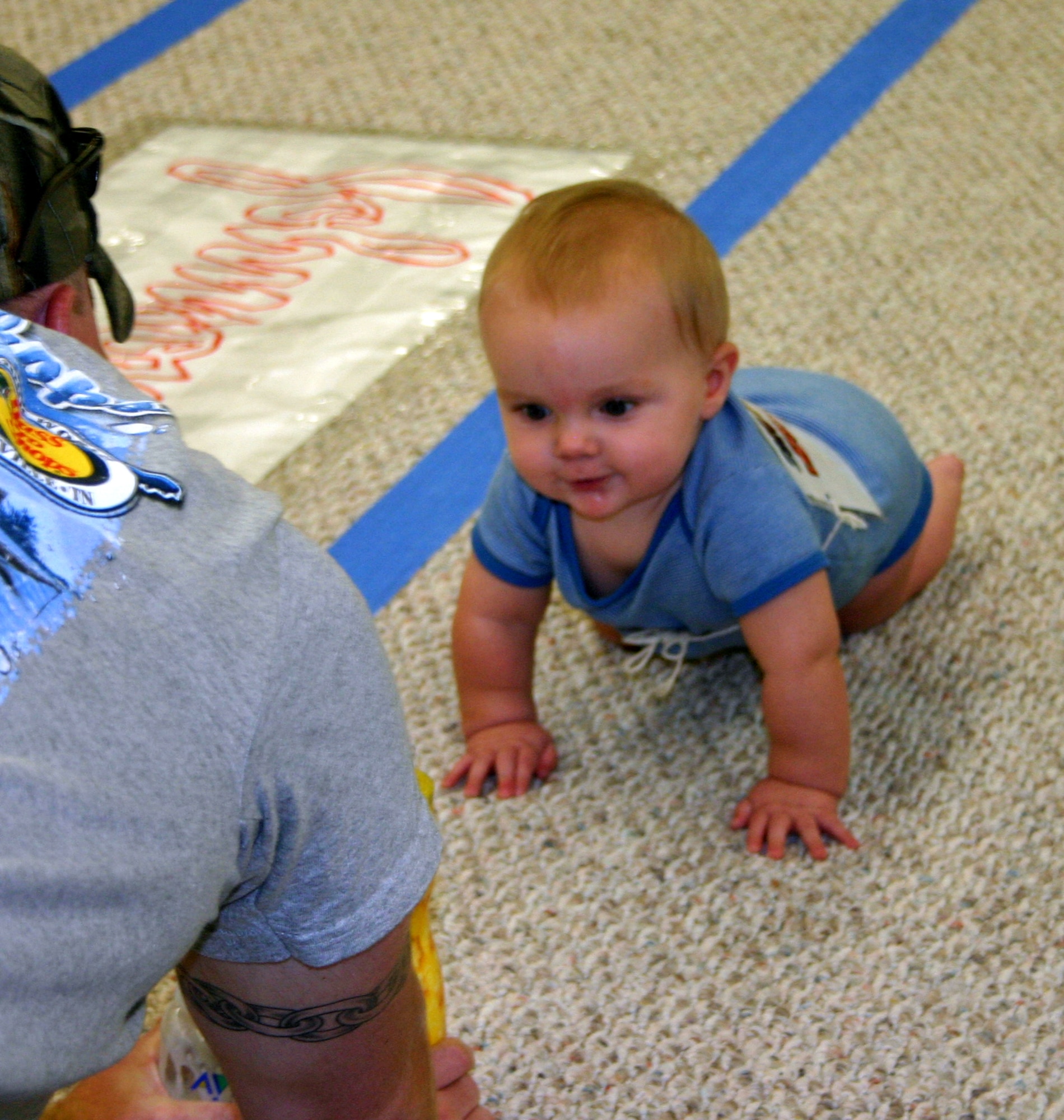 L.J. Sealey focuses in on his goal as his father, Jerry, leads him toward the finish line at the Hotter'N Heck diaper derby Aug. 26.  Sealey won third place in the 0-9 months category. (U.S. Air Force photo/Staff Sgt. Tonnette Thompson)