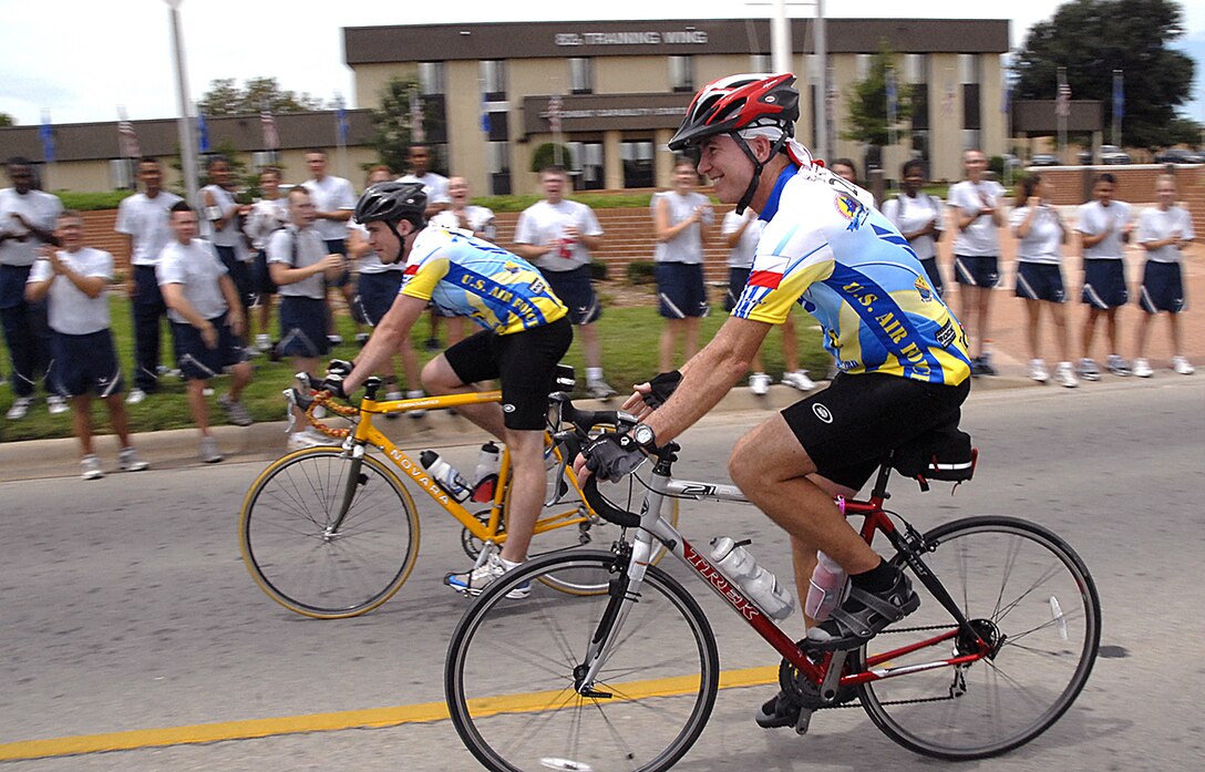 Brig. Gen. Richard Devereaux, 82nd Training Wing commander, rides by the cheering Airmen in Training during the Hotter'N Hell marathon Aug. 25. The race routed the bikers through Sheppard, where the Pitsenbarger Fitness Center had been revamped into a rest stop. (U.S. Air Force photo/Harry Tonemah)