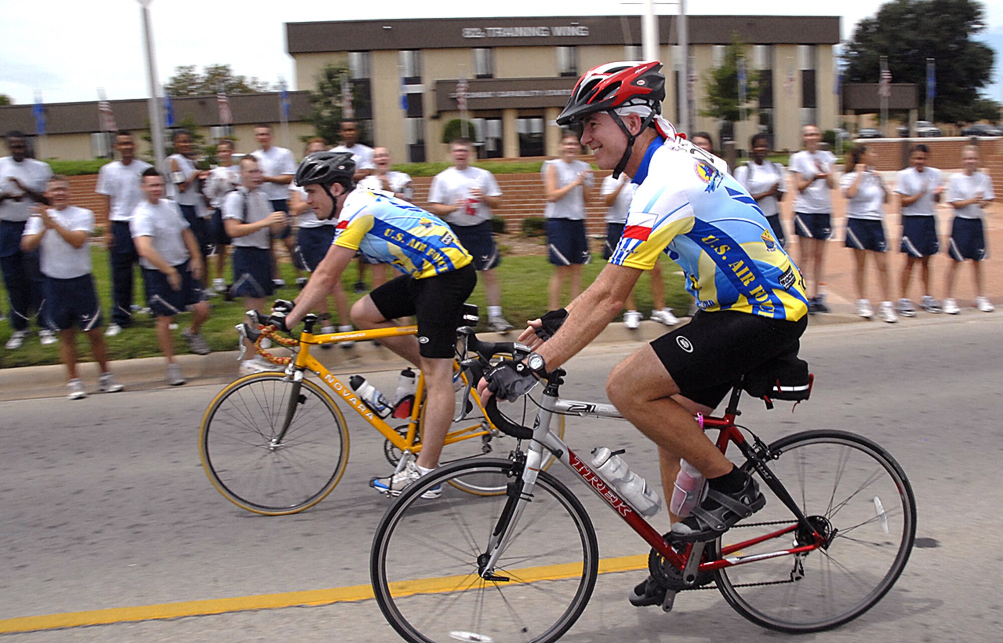 Brig. Gen. Richard Devereaux, 82nd Training Wing commander, rides by the cheering Airmen in Training during the Hotter'N Hell marathon Aug. 25. The race routed the bikers through Sheppard, where the Pitsenbarger Fitness Center had been revamped into a rest stop. (U.S. Air Force photo/Harry Tonemah)