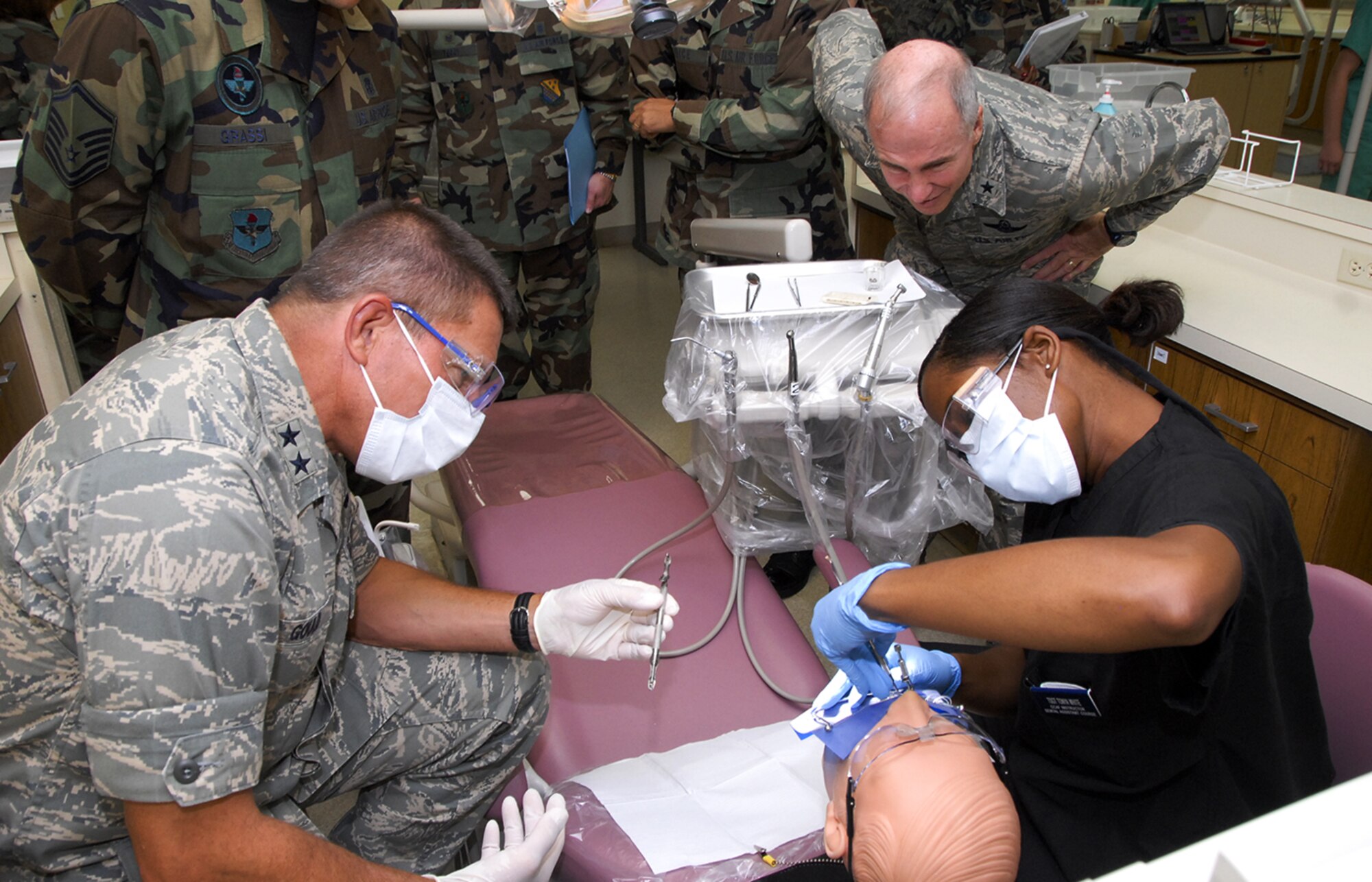 While 82nd Training Wing Commander Brig. Gen. Richard Devereaux looks on, Maj. Gen. Michael Gould, 2nd Air Force commander, assists Tech. Sgt. Tonya White, an instructor with the 82nd Dental Squadron, in creating and implanting a tooth filling.  The 82nd DS was one of General Gould's stops during his tour of Sheppard Aug. 22-26. (U.S. Air Force photo/Harry Tonemah)
