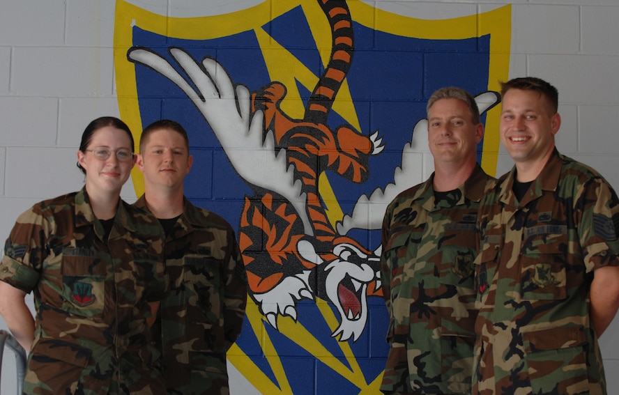 (From left to right) Senior Airman Amanda Stanley, Staff Sgt. Christopher Russell, Tech. Sgt. Patrick Smith, and Tech. Sgt. Jeremy Fisk, 723rd Maintenance Squadron fabrication flight metals technicians, stand before one of seven murals painted on volunteer time over a period of three months. (U.S. Air Force photo by Airman 1st Class Brittany Barker)