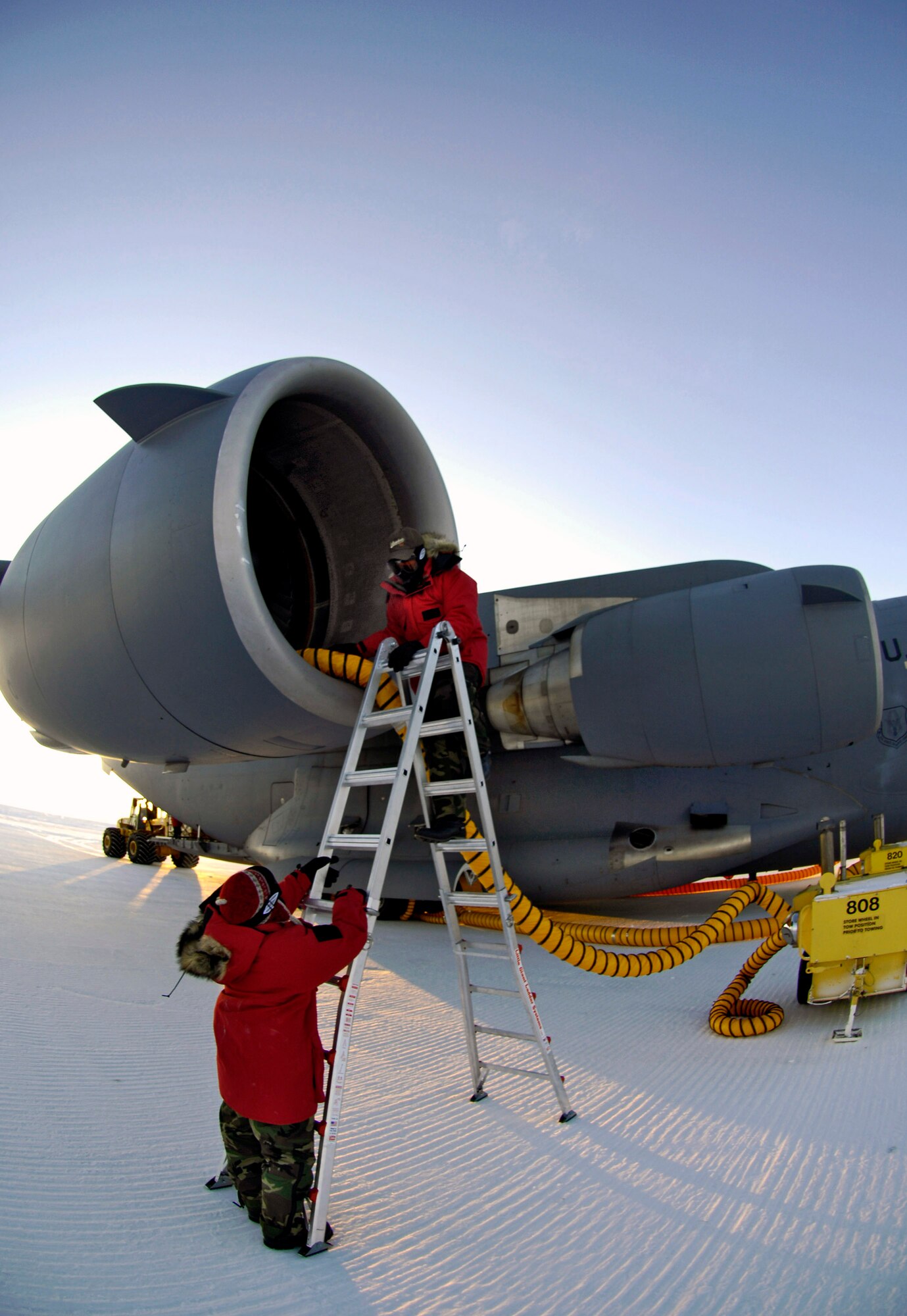 Staff Sgt. Jennifer Torres and Senior Airman Thomas Grover attach heater hoses to the engines of a C-17 Globemaster III for an Operation Deep Freeze winter fly-in mission Aug. 25 at Pegasus White Ice Runway, Antarctica. Because of the extreme temperatures, heaters are used on the aircraft to prevent maintenance problems and keep it functioning properly upon engine start-up. (U.S. Air Force photo/Tech. Sgt. Shane A. Cuomo) 