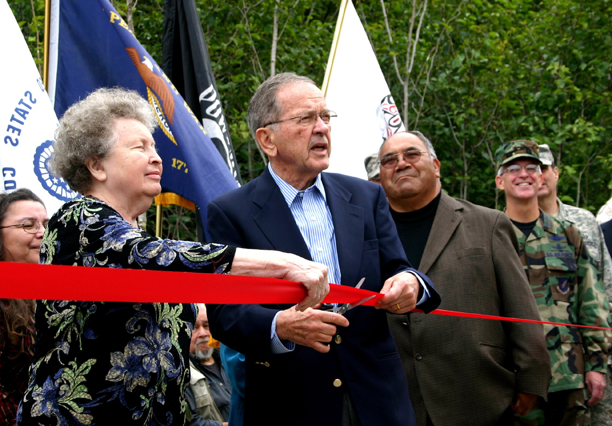 Sen. Ted Stevens cuts the ribbon at the dedication ceremony with Freida Damuss Aug. 6 for the Operation Alaskan Road project in Metlakatla, Alaska. Ms. Damuss also scooped the first shovel of dirt at the beginning of the road project. At right are Mayor Victor Wellington Sr. and Lt. Gen. Douglas Fraser, the commander of Alaskan Command. (U.S. Navy photo/Petty Officer 1st Class Kim McLendon) 
