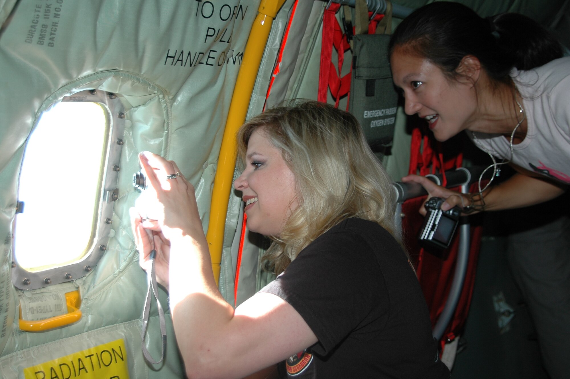 Two Ellsworth spouses take pictures of a B-1 through the window of a KC-135 during an incentive flight Aug. 9. During the flight, the spouses were able to view a refueling procedure from the boom pod of the tanker.