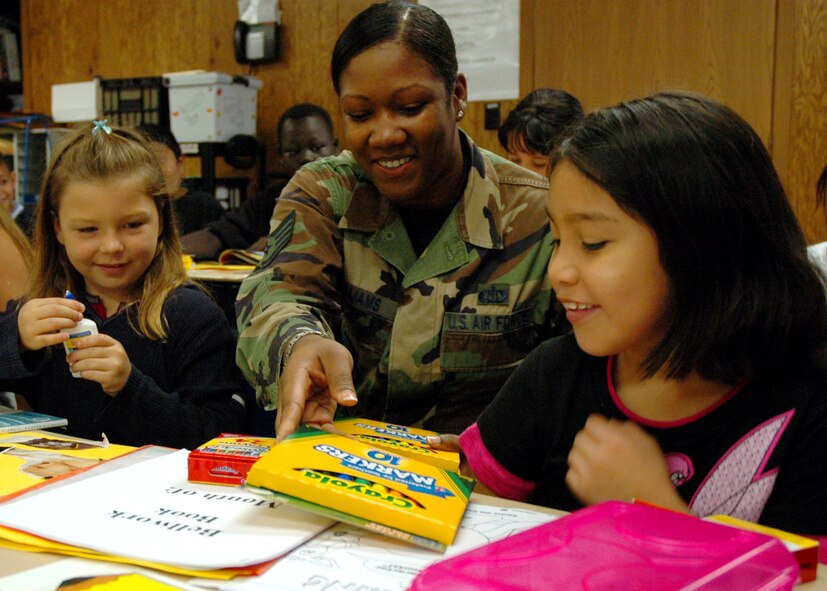 Staff Sgt. Kenyatta Williams, assistant NCO in charge of net-centric database management and data routing for AFWA's 2nd Systems Operations Squadron, helps 8-year-olds Devon Stafford (left) and Sandra Gijon with their new school supplies. An AFWA team collected some 200 pounds of assorted school supplies and delivered them Aug. 23 to Indian Hill Elementary School in Omaha. (Photo by G. A. Volb)