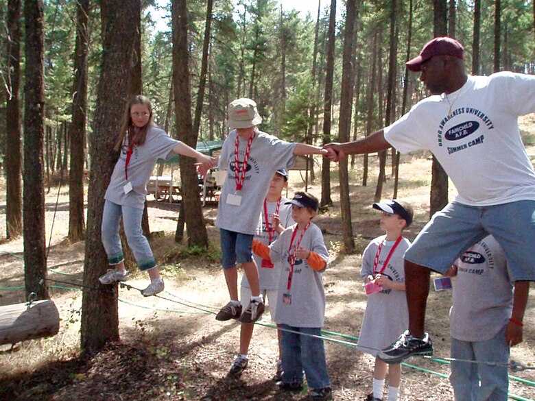 FAIRCHILD AIR FORCE BASE, Wash. – From left, Jerika Boal, Gage Oldenburg, elementary school students here, and Master Sgt. Hubert Cacho, 92nd Contracting Squadron first sergeant, use the teamwork concept to cross a tight-wire obstacle during the Drug Abuse Resistance Education program camp, held Aug. 20-24. The students attended the DARE camp after 10 weeks of classroom training that taught them how to avoid drug, gang and violence involvement, and to resist negative peer pressure. (U.S. Air Force photo / Susan Conard)