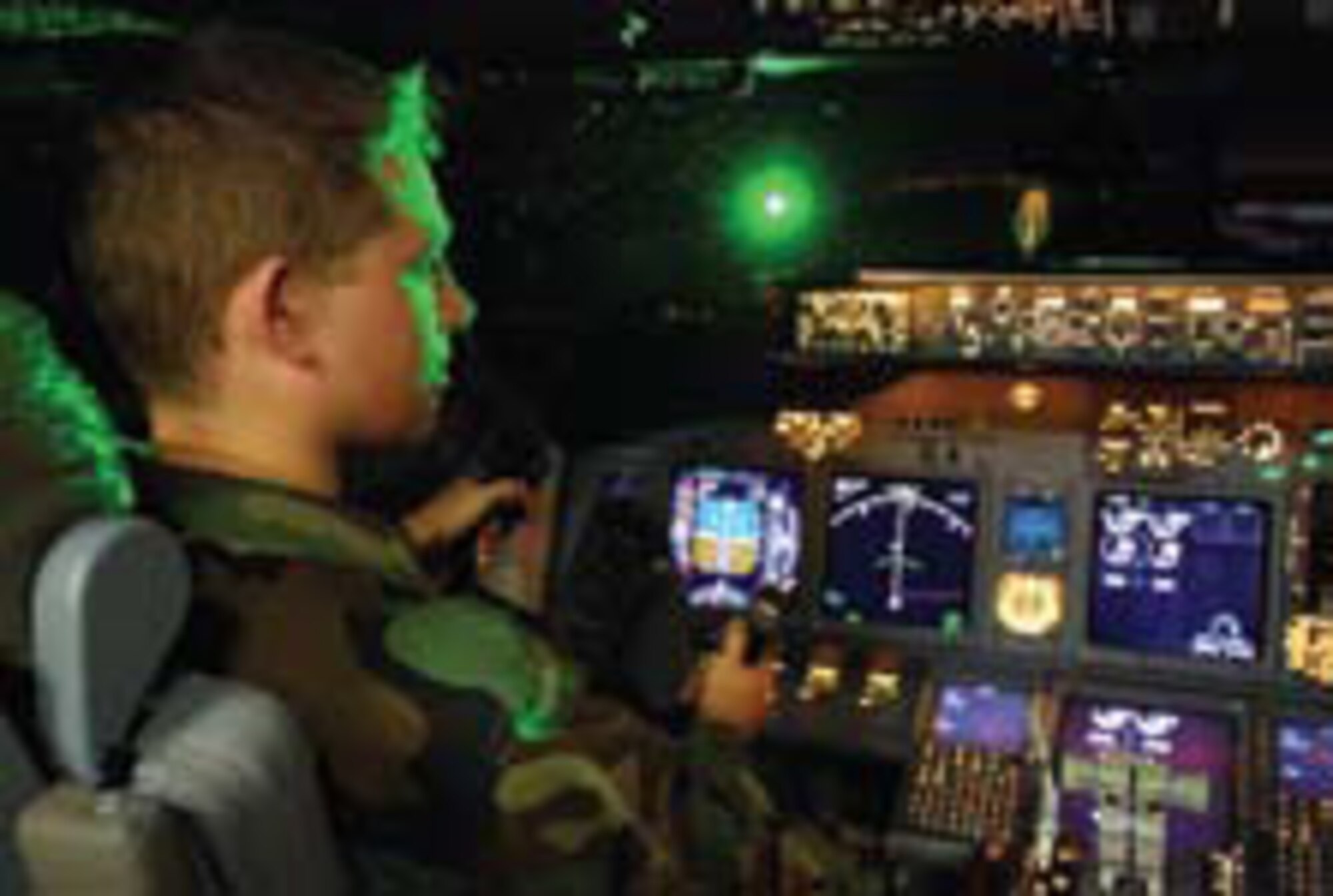 A brilliant flash of green laser light illuminates Air Force Second Lieutenant Paul LaTour during a simulated landing in a Boeing 737 flight simulator at the Federal Aviation Administration’s Mike Monroney Aeronautical Center, Oklahoma City, Oklahoma (photo by Mr. John Schutte, AFRL Human Effectiveness Directorate).
