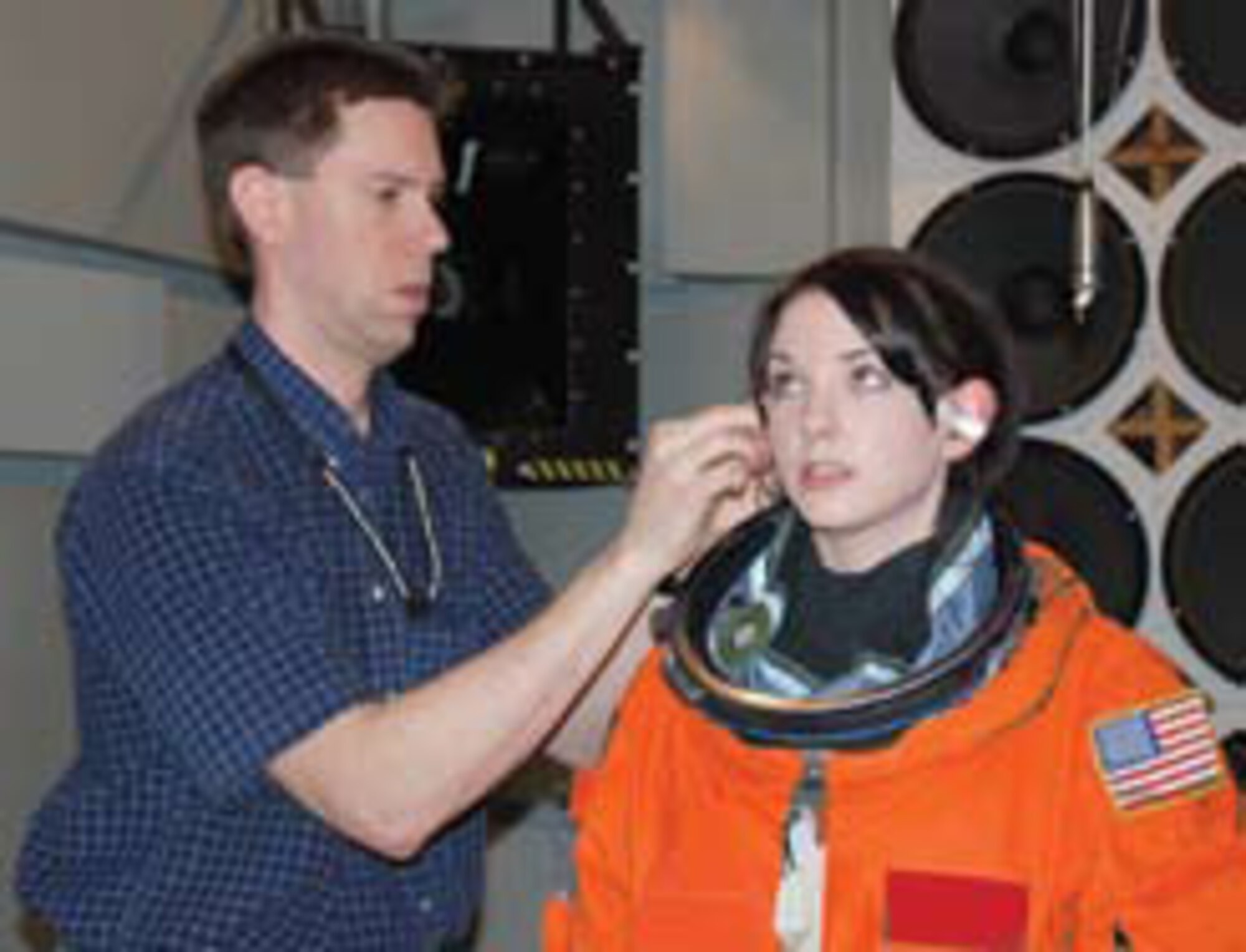 General Dynamics Advanced Information Systems (GDAIS) technician Paul Schley fits miniature microphones in the ears of test subject Beth Greschner, also of GDAIS.  The microphones record sound levels equivalent to those experienced by astronauts during space shuttle liftoff (photo by Chris Gulliford, AFRL Human Effectiveness Directorate).