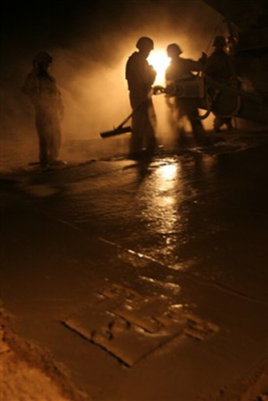 U.S. Marines work at night to lay concrete as they reconstruct a damaged section of road during a route repair mission in the Tharthar region of Al Anbar, Iraq, on Aug. 16, 2007.  The Marines are attached to the 8th Engineer Support Battalion.  