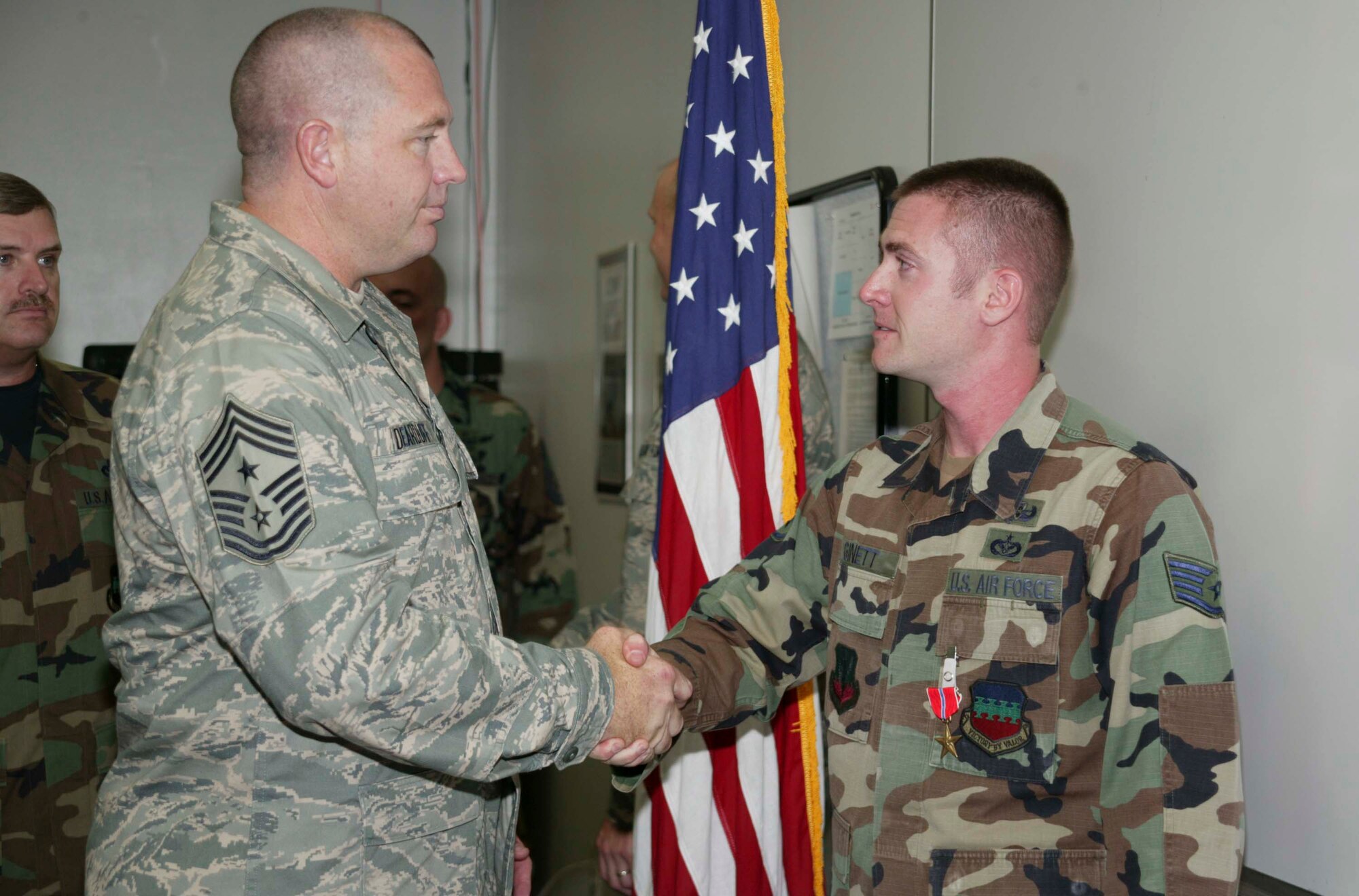SHAW AIR FORCE BASE, S.C. -- Chief Master Sgt. Scott Dearduff, 20th Fighter Wing command chief, congratulates Staff Sgt. Adam Ginett, 20th Civil Engineer Squadron explosive ordnance disposal team leader, for receiving the Bronze Star Medal in the EOD training room Aug. 28. Sergeant Ginnet received the Bronze Star for his service during several operations and taskings in deployed locations. The Bronze Star Medal is awarded to any person who, while serving in any capacity in or with the military of the United States, distinguished himself or herself by heroic or meritorious achievement or service while engaged in an action against an enemy of the United States. (U.S. Air Force photo/Senior Airman Holly MacDonald)