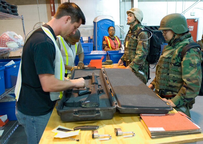 Brian Bailey, supply training manager, inspects and issues a weapon for Airman 1st Class Junghee Cho, a fitness specialist with the 95th Mission Support and Services Squadron, during a recent exercise. Aside from accounting for and issuing weapons, the supply group issues mobility bags to Airmen creating a one-stop solution for Airmen prior to deploying. (Photo by Mike Cassidy)
