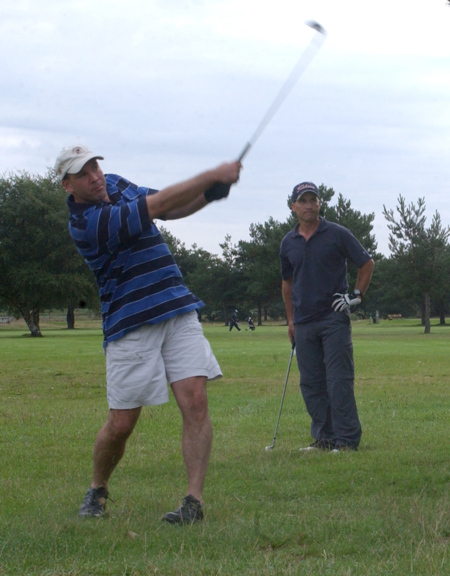 Joe Peery, 100th Mission Support Squadron, playing a short iron shot into the seventh green in the semi-finals of intramural golf at Breckland Pines Golf Club, Aug. 28, with playing partner Mark Gagnon looking on. (Air Force photo by Airman Brad Smith)