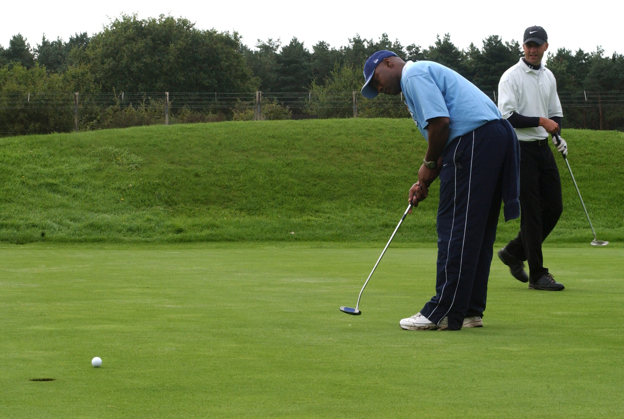 John Robertson, 100th Aircraft Maintenance Squadron putting on the ninth green in the semi-finals of intramural golf at Breckland Pines Golf Club, Aug. 28, with partner Antonio Barranca checking his line. (Air Force photo by Airman Brad Smith)
