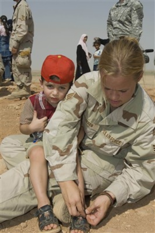 U.S. Air Force Senior Airman Ashley-Louise Jacobsen helps an Iraqi boy get a rock out of his sandal during a visit to a historical ziggurat located on Ali Air Base, Iraq, on Aug. 21, 2007.  Jacobsen is attached to the 407th Expeditionary Logistics Readiness Squadron.  