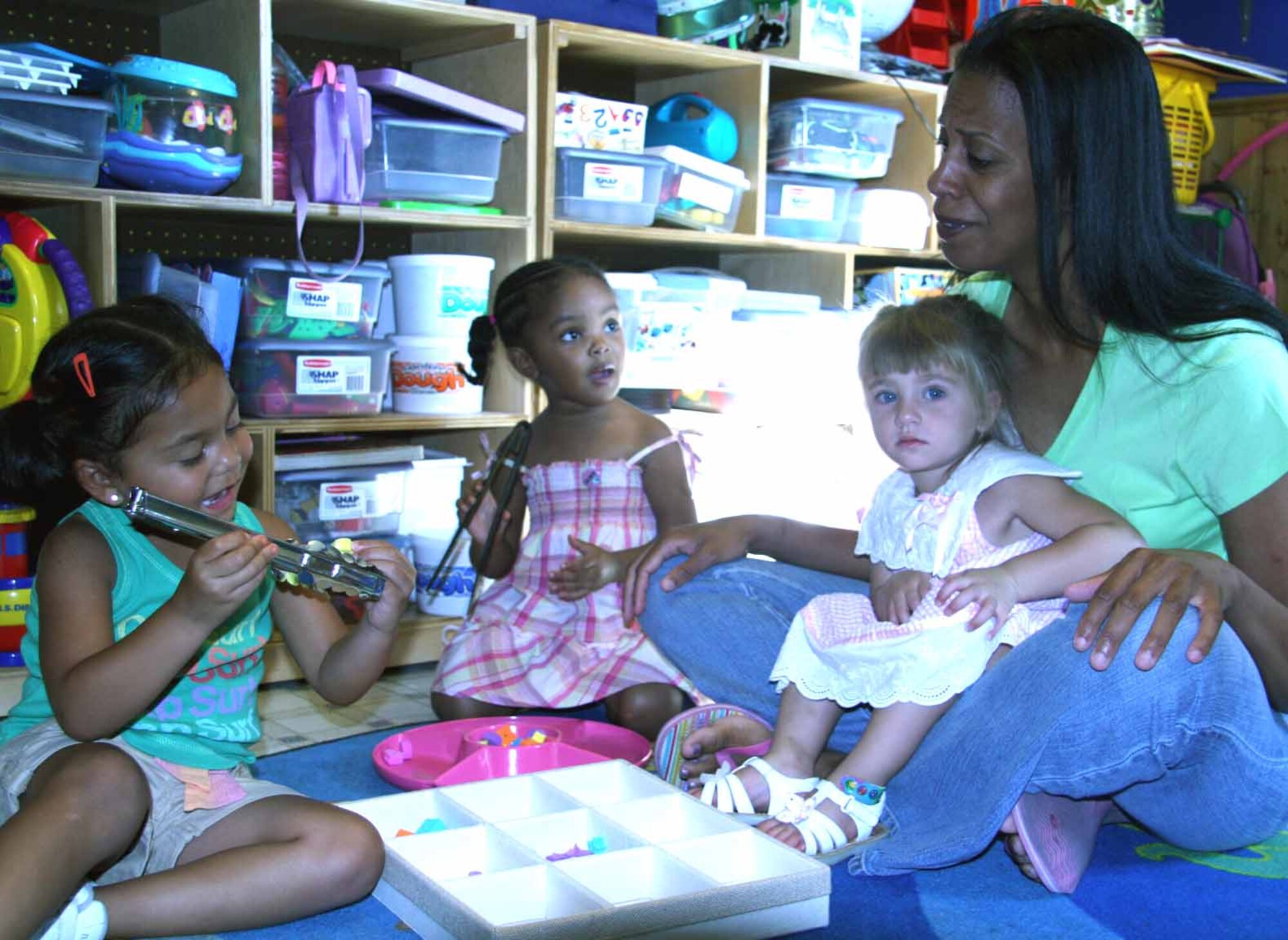 Provider Becci Roe teaches, from left, Willow Roe, 3; Amina Blackson, 3; and Lilyenne Hyland, 2, about different shapes. (Air Force photo by Becky Pillifant)