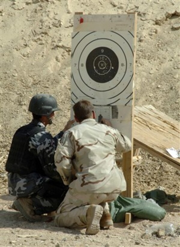 A U.S. Army soldier (right) from the 3rd Battalion, 10th Special Forces Group reviews a target while assisting an Iraqi Special Weapons and Tactics team member with properly sighting in his weapon during training at Camp Hit, Iraq, on Aug. 26, 2007. 