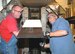 (From left) Aerospace Testing Alliance Outside Machinists Gary Cunningham and R.B. Ray install an External Tank Thermal Protection System foam sample tile prior to injection into Tunnel C which was already running at Mach 4 and 1,440 degrees Fahrenheit. The TPS foam protects the shuttle's ET during ascent. (Photo by David Housch)