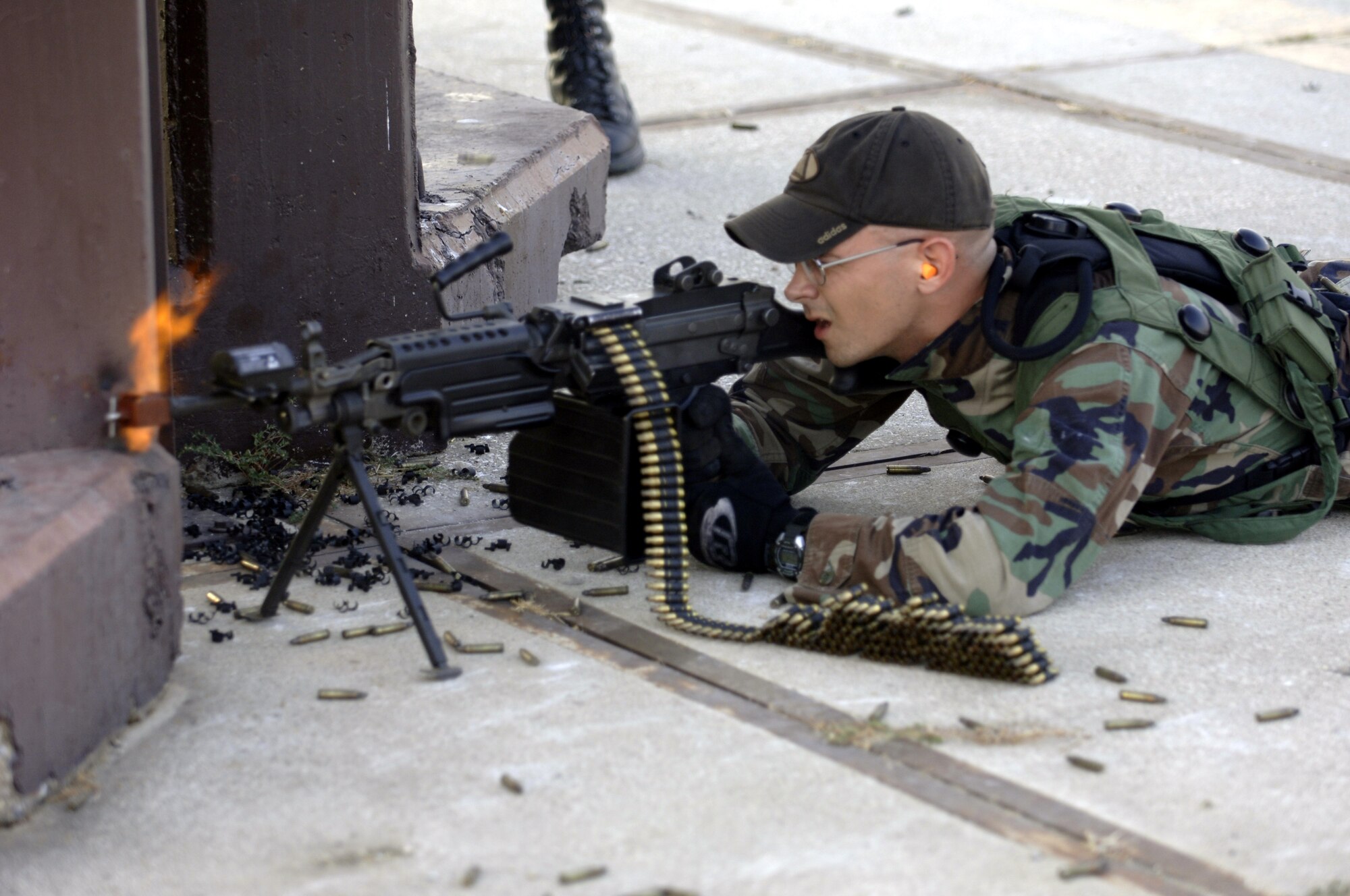Senior Airman Joe Hess, 39th Maintenance Squadron conventional stock pile management, discharges his 249 machine gun from his defensive fighting position as members of the 39th Security Forces Squadron approach his position during the force on force exercise on the flightline Aug. 21. Members from both sides are suited with Multiple Integrated Laser Engagement System. MILES gear use lasers and blank cartridges to simulate actual battle for training purposes. (U. S. Air Force photo by Airman 1st Class Nathan Lipscomb)
