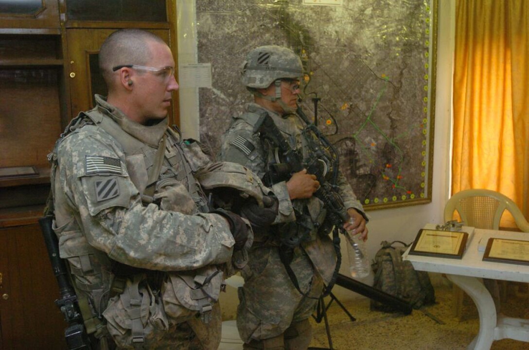Army 1st Lt. Mike Barth and Staff Sgt. Sean Kane watch during a ceremony in Jisr Diyala, Iraq, to recognize the valor of a young man who died preventing a suicide bomber from killing U.S. soldiers and Iraqi civilians on Aug. 23. Photo by Spc. Ben Hutto, USA