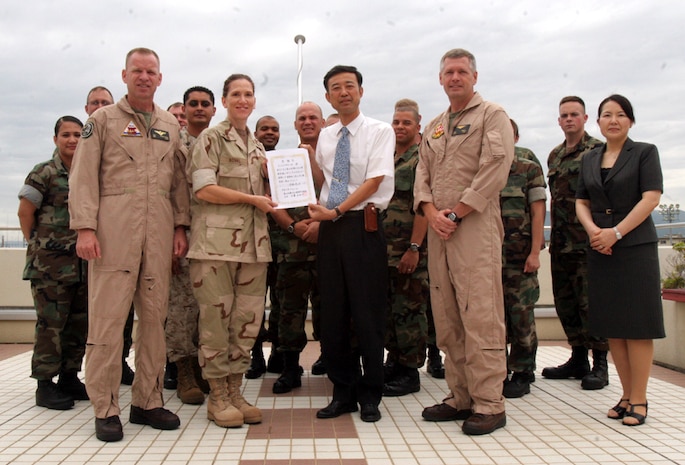 A member of the Iwakuni City council hands a letter of appreciation to Senior Chief Petty Officer Alicia Koval, Expeditionary Logistics Unit leading chief petty officer and coordinator of the Nishiki River cleanup effort, for their volunteer work on Aug. 26.