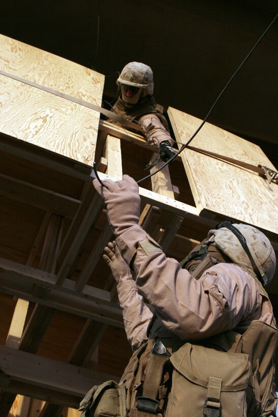 NEAR AR RUTBAH, Iraq - Cpl. Allen Macleod lowers detonation cord to Lance Cpl. Andrew Wilson as they work to wire explosive charges set underneath Bridge 18, Dec. 2. Both Marines are combat engineers with Charlie Company, 1st Combat Engineer Battalion, Regimental Combat Team 2,