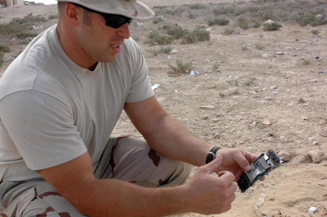 SOUTHWEST ASIA - Tech. Sgt. David Fitzgerald, 379th Expeditionary Civil Engineer Squadron Explosive Ordinance Disposal, examines the remains of a simulated detonation device. The 379th EOD unit attaches small explosive charges to bottles of water that accelerate the water out and cause it to cut through the container without using fire or heat. (U.S. Air Force photo/Staff Sgt. Jason Barebo)