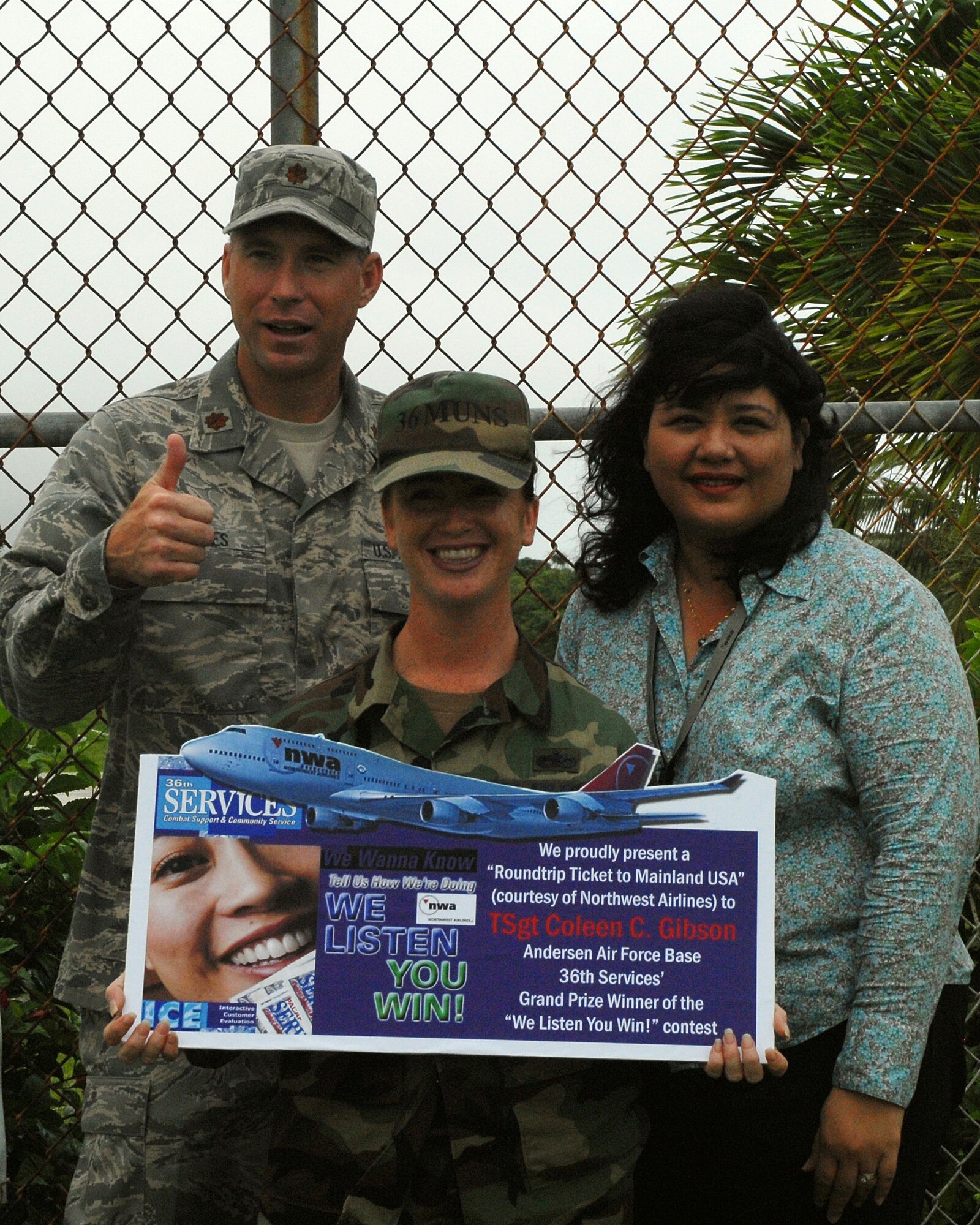 Out of six grand prize winners in the Pacific Air Forces who participated in the “We Listen, You Win” Services command-wide comment card promotion, Tech. Sgt. Coleen Gibson, 36th Wing, was one of the lucky winners to win roundtrip airline tickets to travel to any destination in the U.S.  The award was presented to her by Maj. Alex Gaines, 36th Services Squadron commander, and Marie Lizama, Northwest Airlines representative, on Nov. 28.  (U.S. Air Force photo/Angelica Covington)