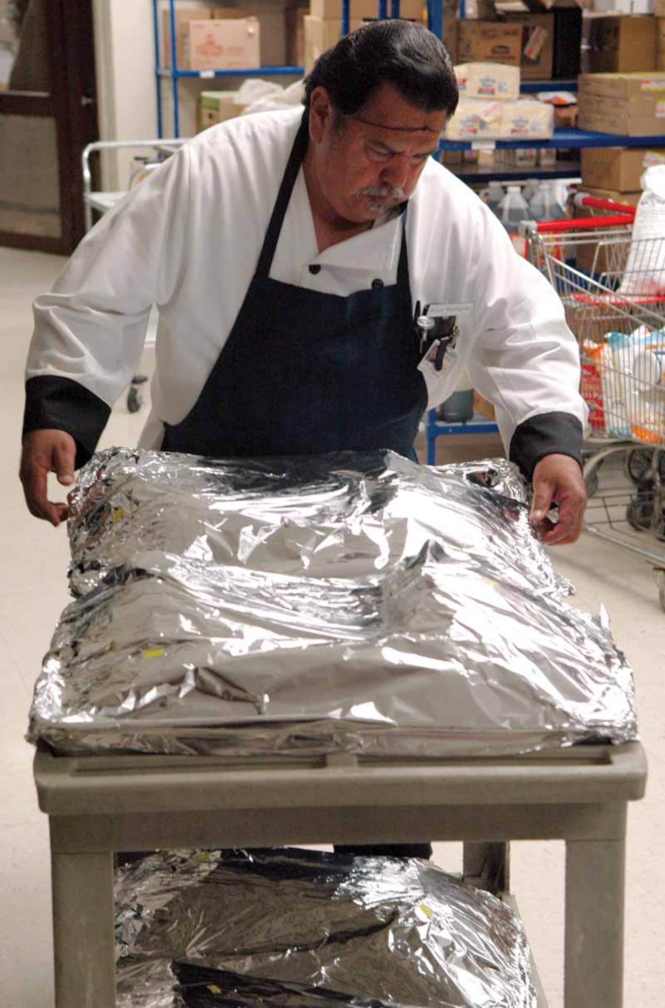 Senior Cook Angel “Rod” Rodriques adds one more turkey to his cart.  Mr. Rodriques seasoned 18 turkeys that were stored in an industrial size refrigerator until time for them to go into the oven Wednesday night. Before dinner was served Mr. Rodriques cooked more than 390 pounds of turkey for Thanksgiving dinner. (Air Force photo by Kathy Paine)
