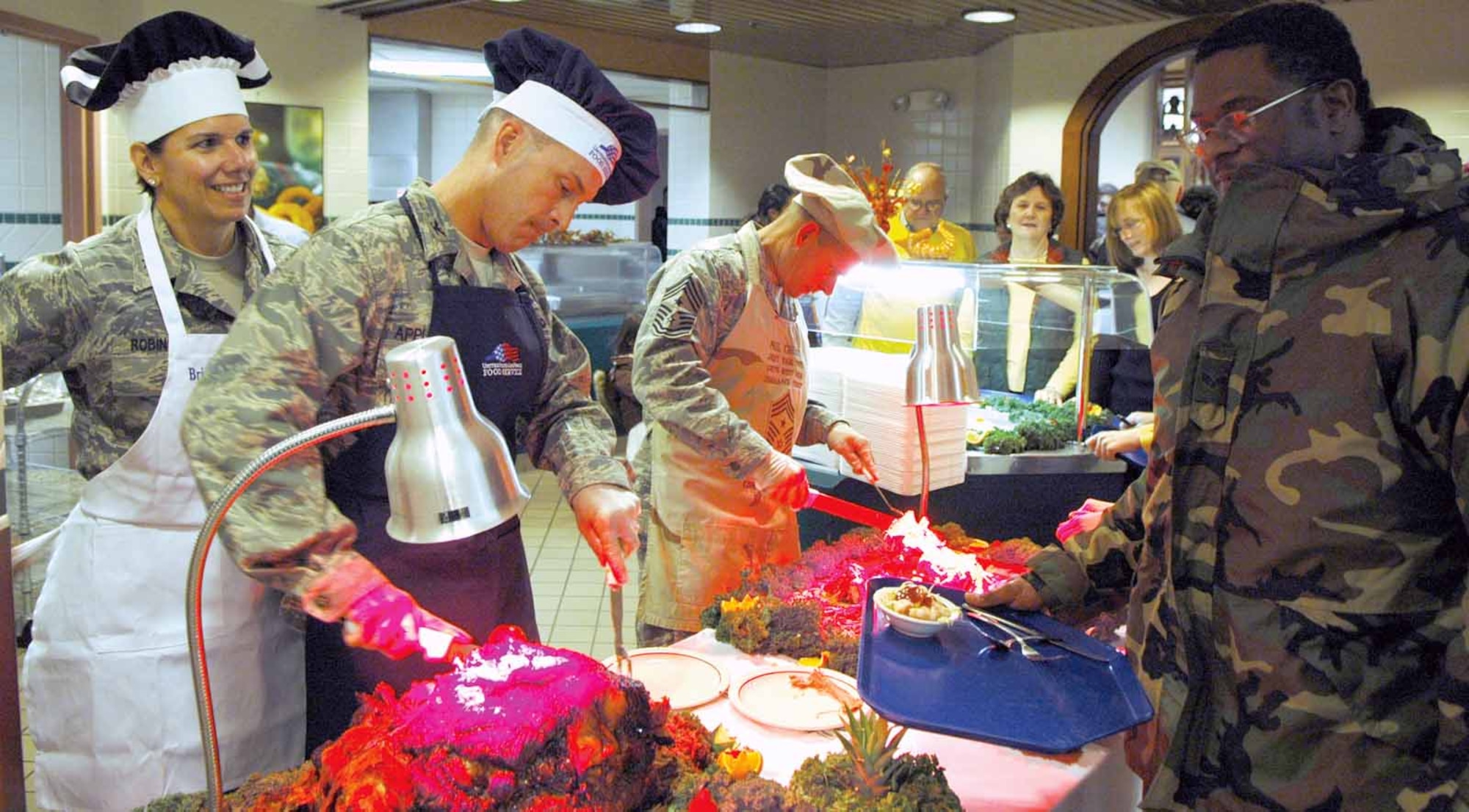 Col. James Appleyard, 3rd Combat Communication Group commander, and Command Chief Master Sgt. Phillip Cherry serve Senior Airman Paul Travis, who enjoyed Thanksgiving dinner with his sons. Brig. Gen. Lori Robinson, 552nd Air Control Wing commander, was on hand to assist as needed. (Air Force photo by Kathy Paine)