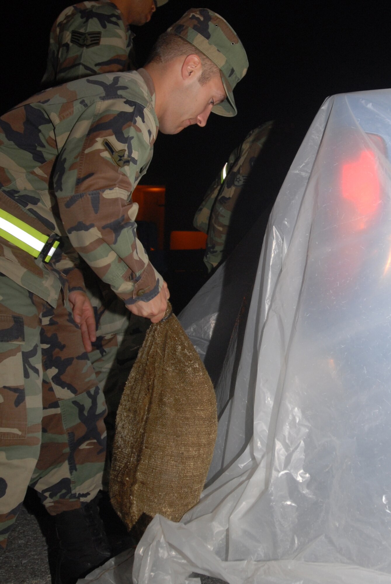 Airmen from the 18th Logistics Readiness Squadron, Vehicle Operations Section secure plastic around a pick-up truck with sandbags in preparation for a simulated chemical attack during Local Operational Readiness Exercise Beverly High 08-2 at Kadena Air Base, Japan, Dec. 3, 2007. These scenarios enable base agencies to work together, mitigate real-world situations, and heighten readiness capabilities.
(U.S. Air Force photo/Staff Sgt. Chrissy FitzGerald)
