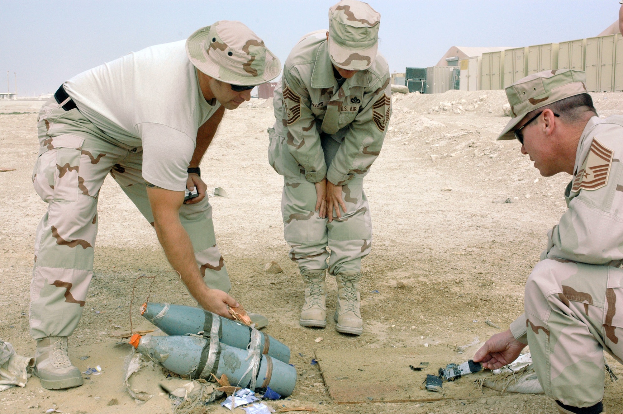 Tech. Sgt. David Fitzgerald (left), from the 379th Expeditionary Civil Engineer Squadron's explosive ordnance disposal branch, shows Chief Master Sgts. Suzanne Phillips and John O'Brien the remains of a simulated improvised explosive device.  The chiefs are also with the 379th ECES.  (U.S. Air Force photo/Staff Sgt. Jason Barebo)