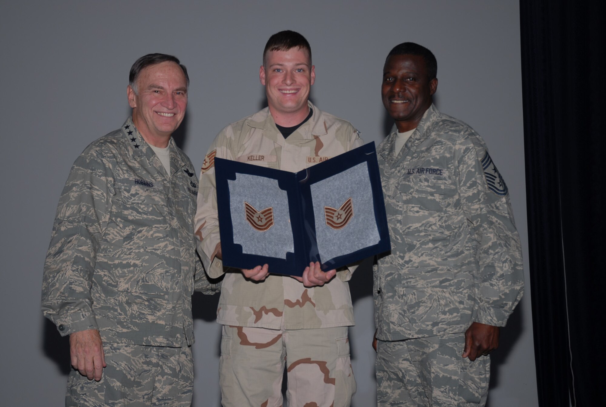SOUTHWEST ASIA - Gen.Tom Hobbins, United States Air Forces Europe commander, and  Chief Master Sgt. Gary Coleman,  USAFE command chief master sergeant , surprise Staff Sgt. Collin Keller, 379th Expeditionary Security Forces Squadron, with a Stripes Through Exceptional Performance promotion to technical sergeant Nov. 30 at a Southwest Asia air base. Sergeant Keller is deployed from Spangdahlem AB, Germany. (U. S. Air Force photo/Staff Sgt. Douglas Olsen)